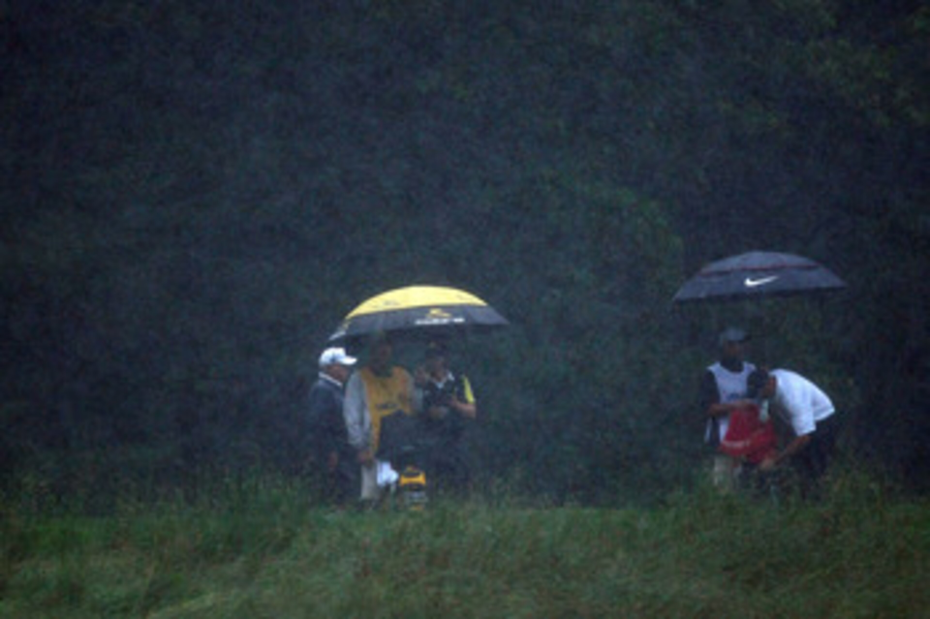 FARMINGDALE, NY - JUNE 20:  Camilo Villegas of Colombia and Stewart Cink stand with their caddies under umbrellas in the rain during the third round of the 109th U.S. Open on the Black Course at Bethpage State Park on June 20, 2009 in Farmingdale, New Yor