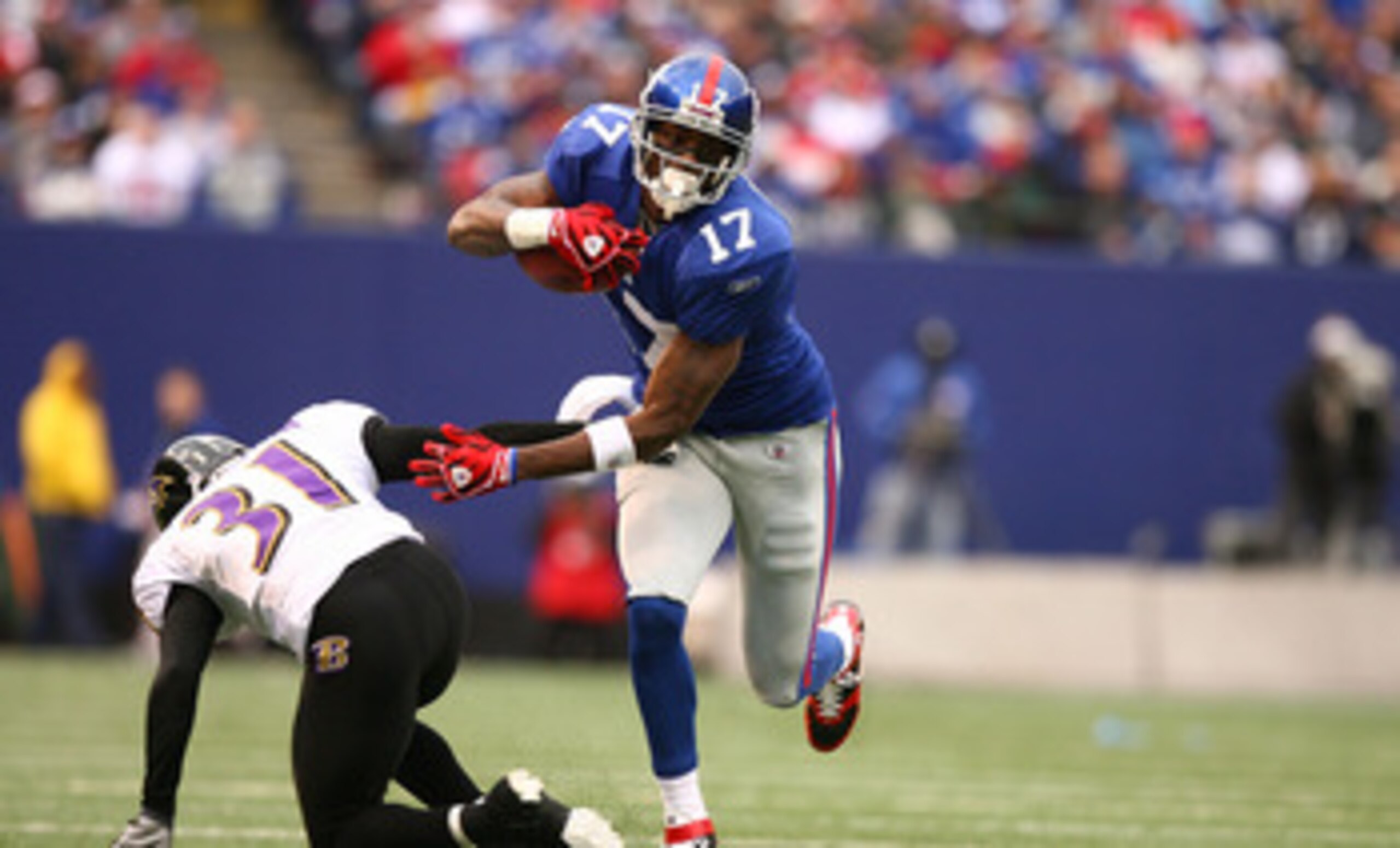 EAST RUTHERFORD, NJ - NOVEMBER 16:  Plaxico Burress #17 of the New York Giants eludes the tackle of Fabian Washington #31 of the Baltimore Ravens during their game on November 16, 2008 at Giants Stadium in East Rutherford, New Jersey.  (Photo by Al Bello/