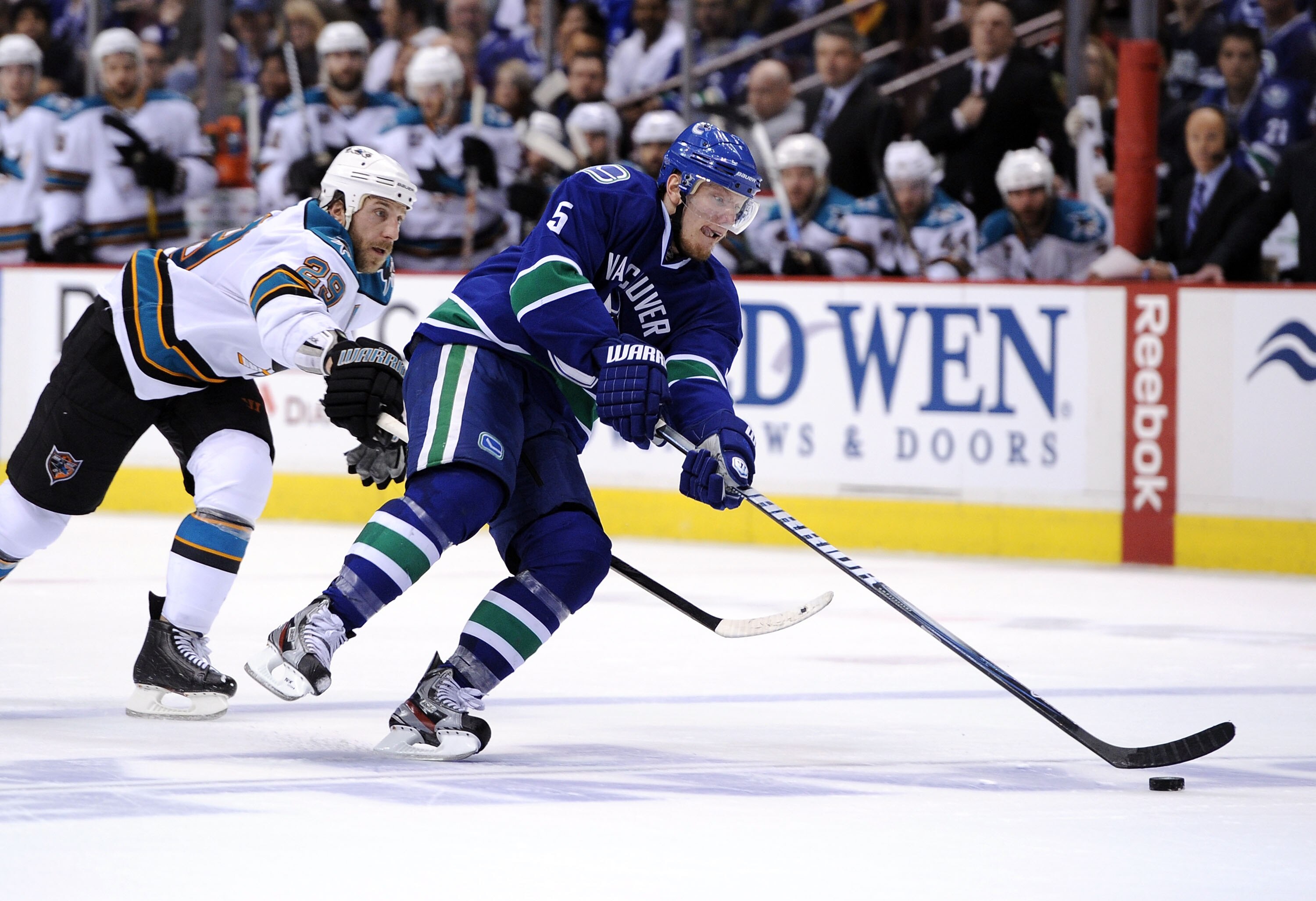 VANCOUVER, CANADA - MAY 15:  Christian Ehrhoff #5 of the Vancouver Canucks controls the puck under pressure from Ryane Clowe #29 of the San Jose Sharks in Game One of the Western Conference Finals during the 2011 Stanley Cup Playoffs at Rogers Arena on Ma