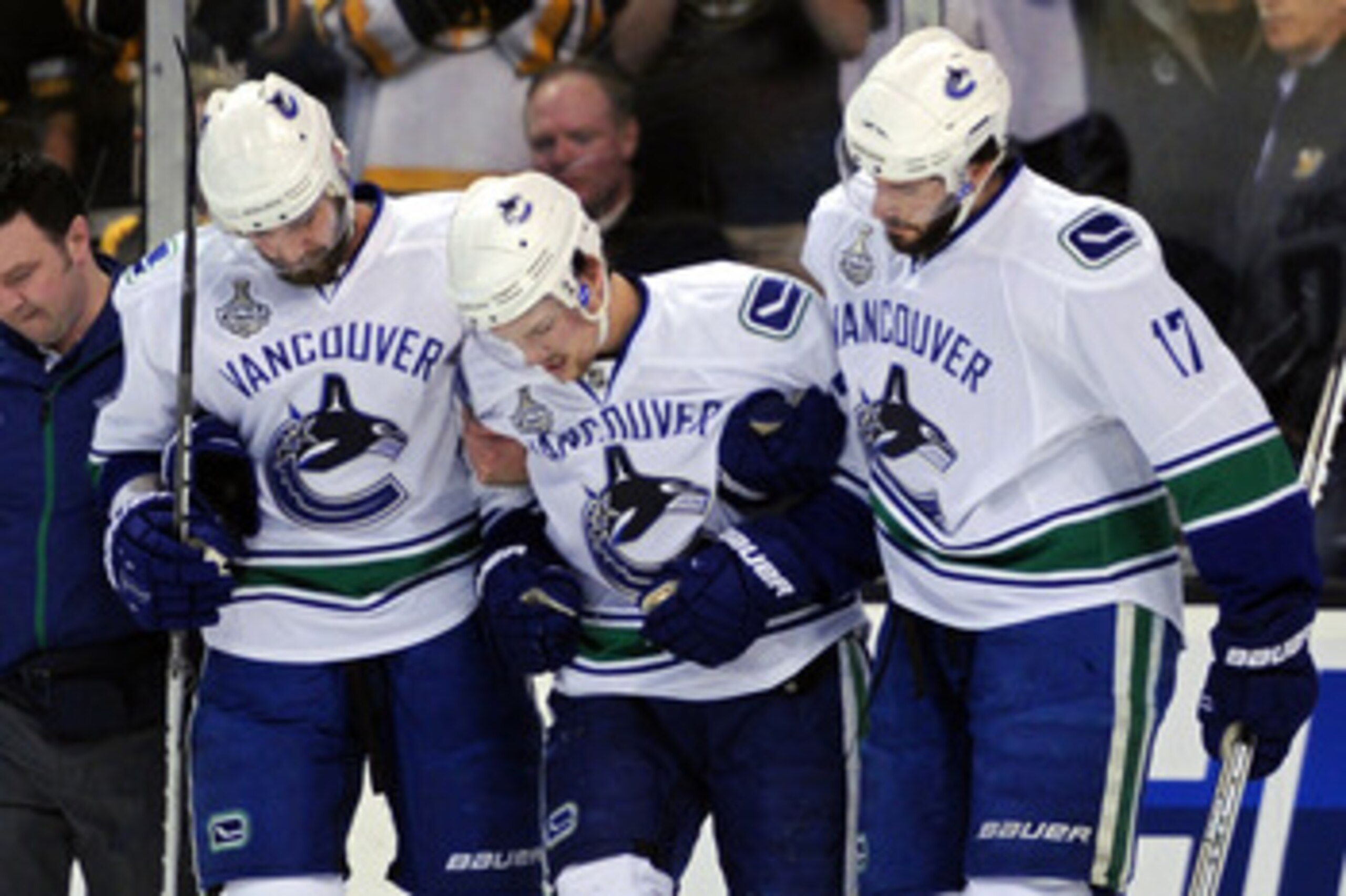 BOSTON, MA - JUNE 13:  Christopher Higgins #20 and Ryan Kesler #17 help Mason Raymond #21 of the Vancouver Canucks off the ice after being checked by Johnny Boychuk #55 of the Boston Bruins in the first period during Game Six of the 2011 NHL Stanley Cup F