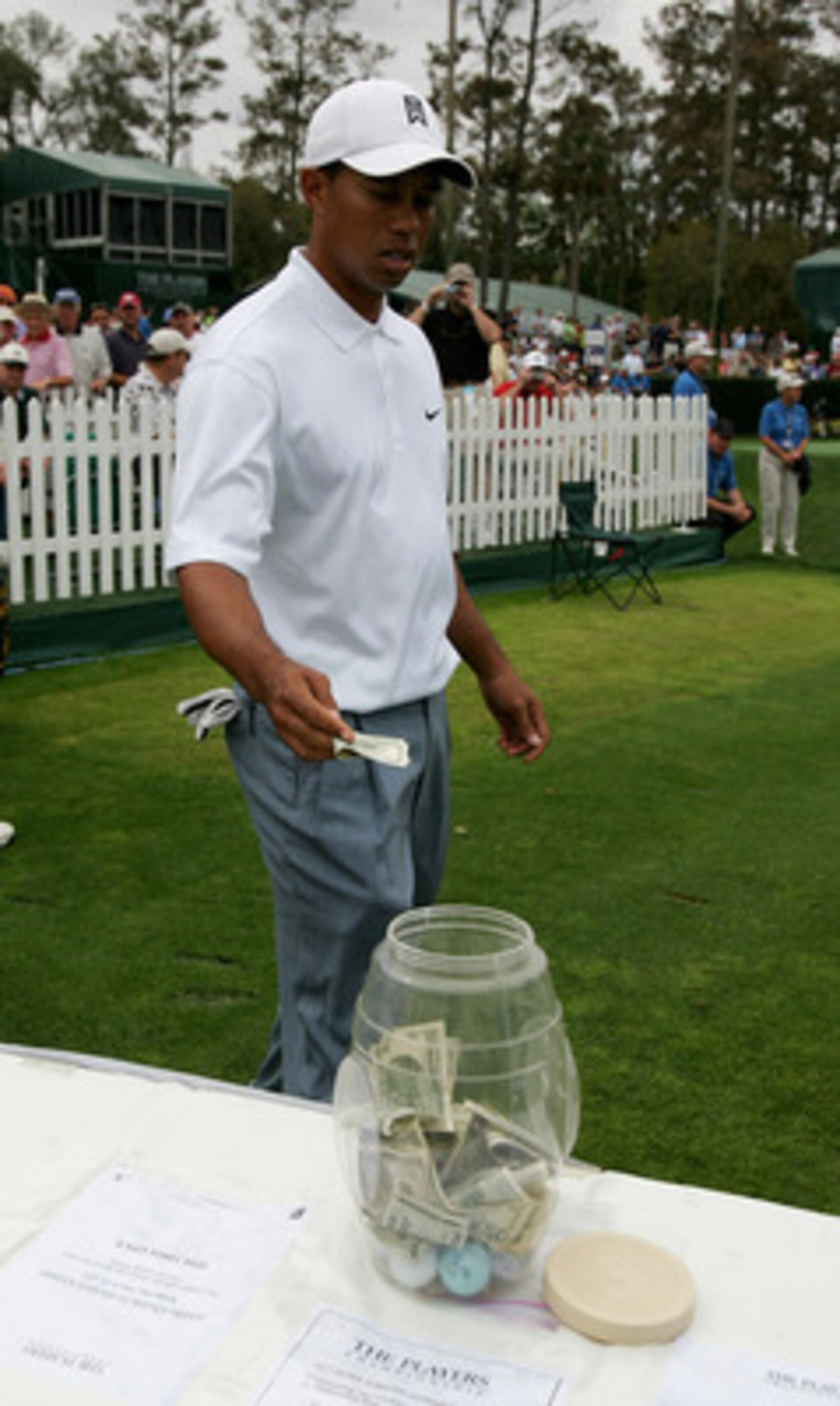 PONTE VEDRA BEACH, FL - MARCH 23: Tiger Woods thows a one hundred dollar bill into the charity pot on the 17th tee during practice prior to The Players Championship at the TPC at Sawgrass on March 23, 2005 in Ponte Vedra Beach, Florida. (Photo by Richar PONTE VEDRA BEACH, FL - MARCH 23: Tiger Woods thows a one hundred dollar bill into the charity pot on the 17th tee during practice prior to The Players Championship at the TPC at Sawgrass on March 23, 2005 in Ponte Vedra Beach, Florida. (Photo by Richar