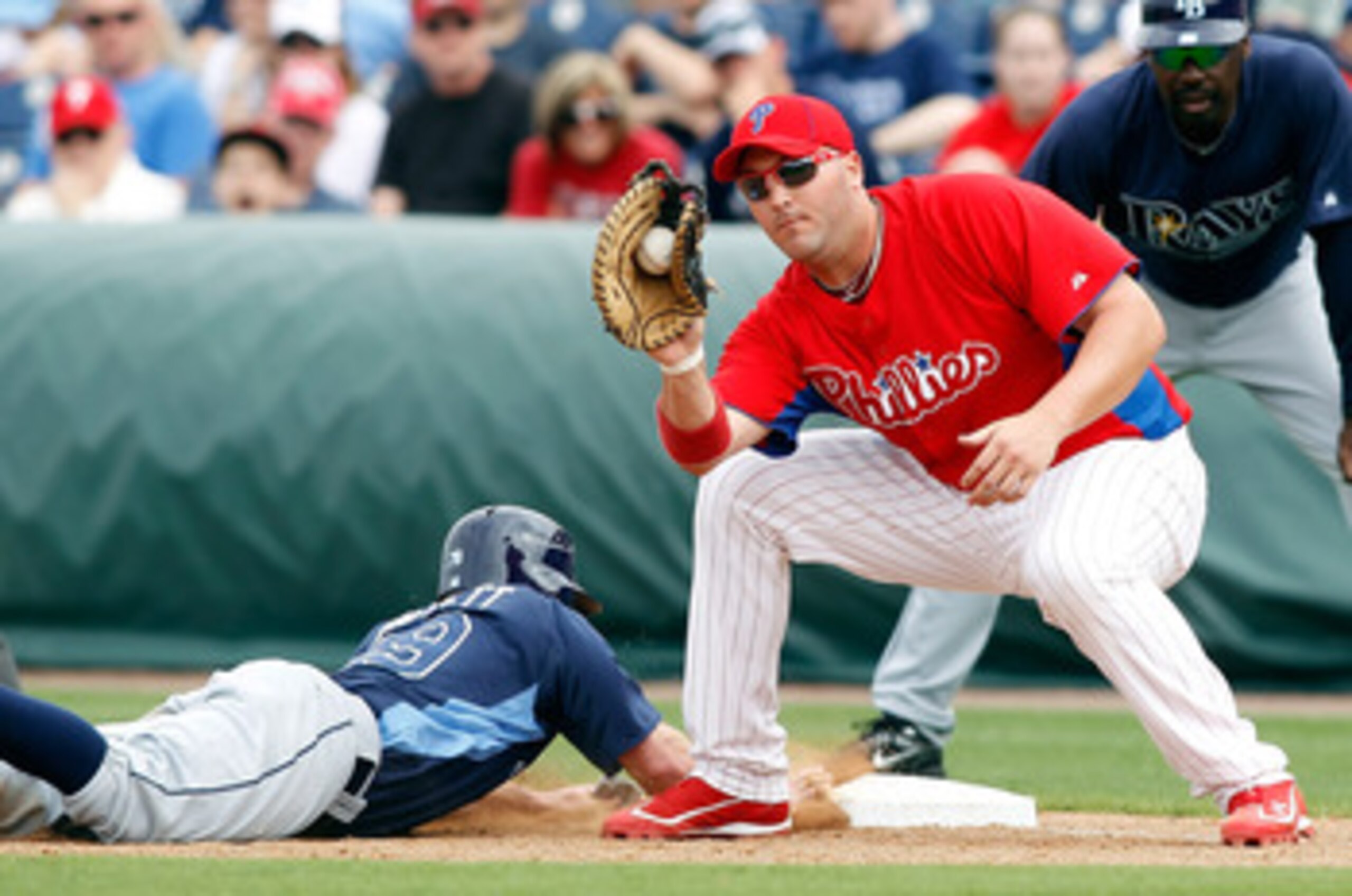 CLEARWATER, FL - MARCH 06:  First baseman Matt Rizzotti #76 of the Philadelphia Phillies takes the throw at first as Joe Inglett #79 of the Tampa Bay Rays gets back safely during a Grapefruit League Spring Training Game at Bright House Field on March 6, 2