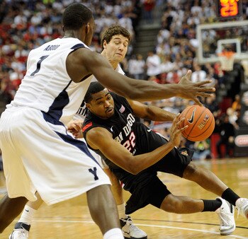 LAS VEGAS, NV - MARCH 12:  Chase Tapley #22 of the San Diego State Aztecs falls to the court as he drives against Charles Abouo #1 and Jimmer Fredette #32 of the Brigham Young University Cougars during the championship game of the Conoco Mountain West Con