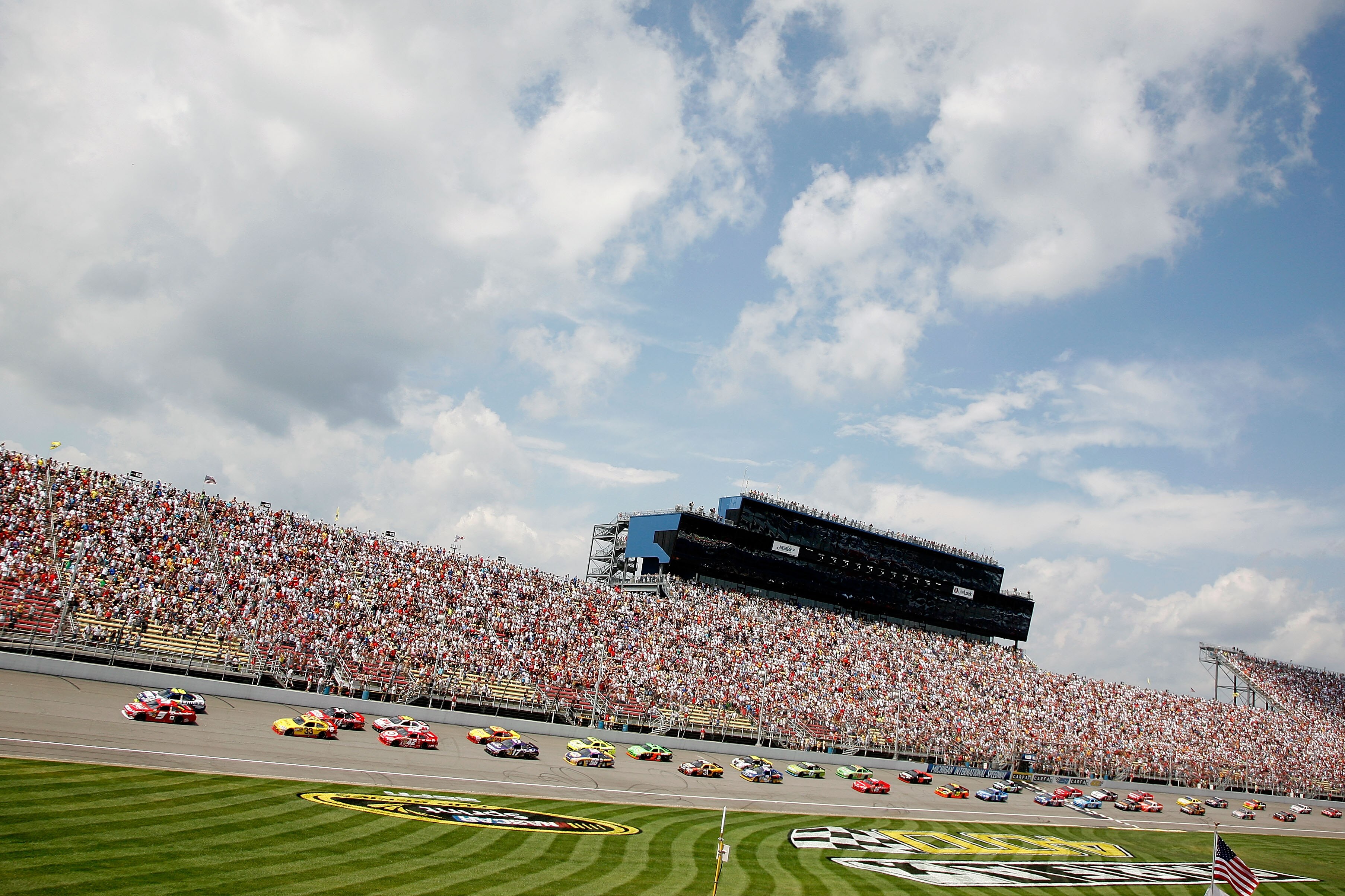 BROOKLYN, MI - AUGUST 15: Kasey Kahne, driver of the #9 Budweiser Ford and Jimmie Johnson, driver of the #48 Lowe's Chevrolet, lead the field at the start of the NASCAR Sprint Cup Series CARFAX 400 at Michigan International Speedway on August 15, 2010 in