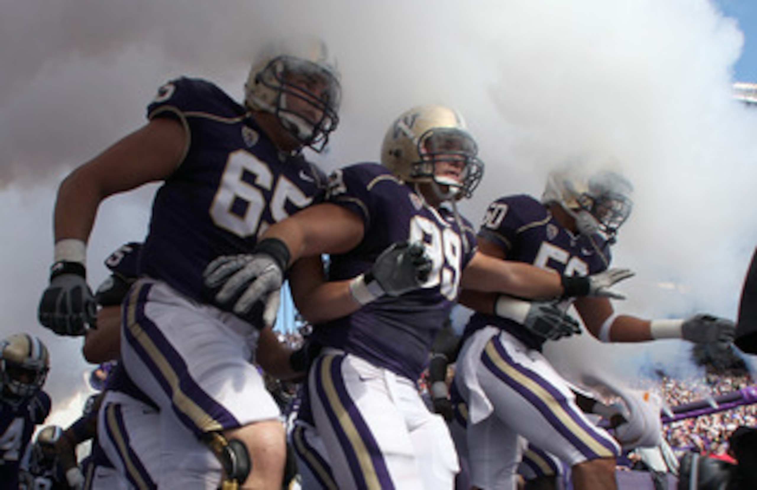 SEATTLE - SEPTEMBER 18:  Ryan Tolar #65, Cameron Elisara #99, and Kalani Aldrich #50 of the Washington Huskies run out of the tunnel prior to the game against the Nebraska Cornhuskers on September 18, 2010 at Husky Stadium in Seattle, Washington. The Corn