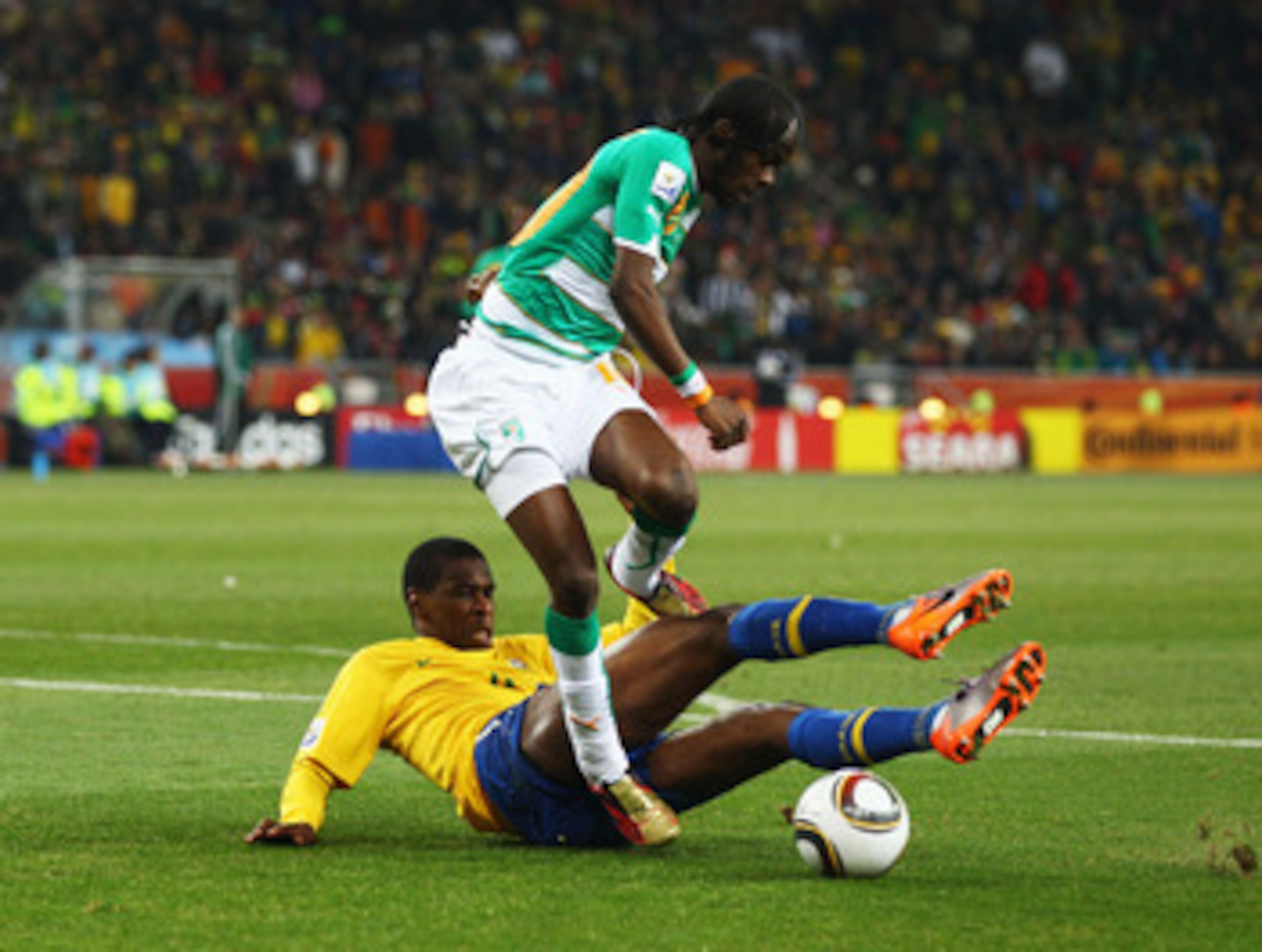 JOHANNESBURG, SOUTH AFRICA - JUNE 20: Juan of Brazil tackles Gervinho of Ivory Coast during the 2010 FIFA World Cup South Africa Group G match between Brazil and Ivory Coast at Soccer City Stadium on June 20, 2010 in Johannesburg, South Africa.  (Photo by