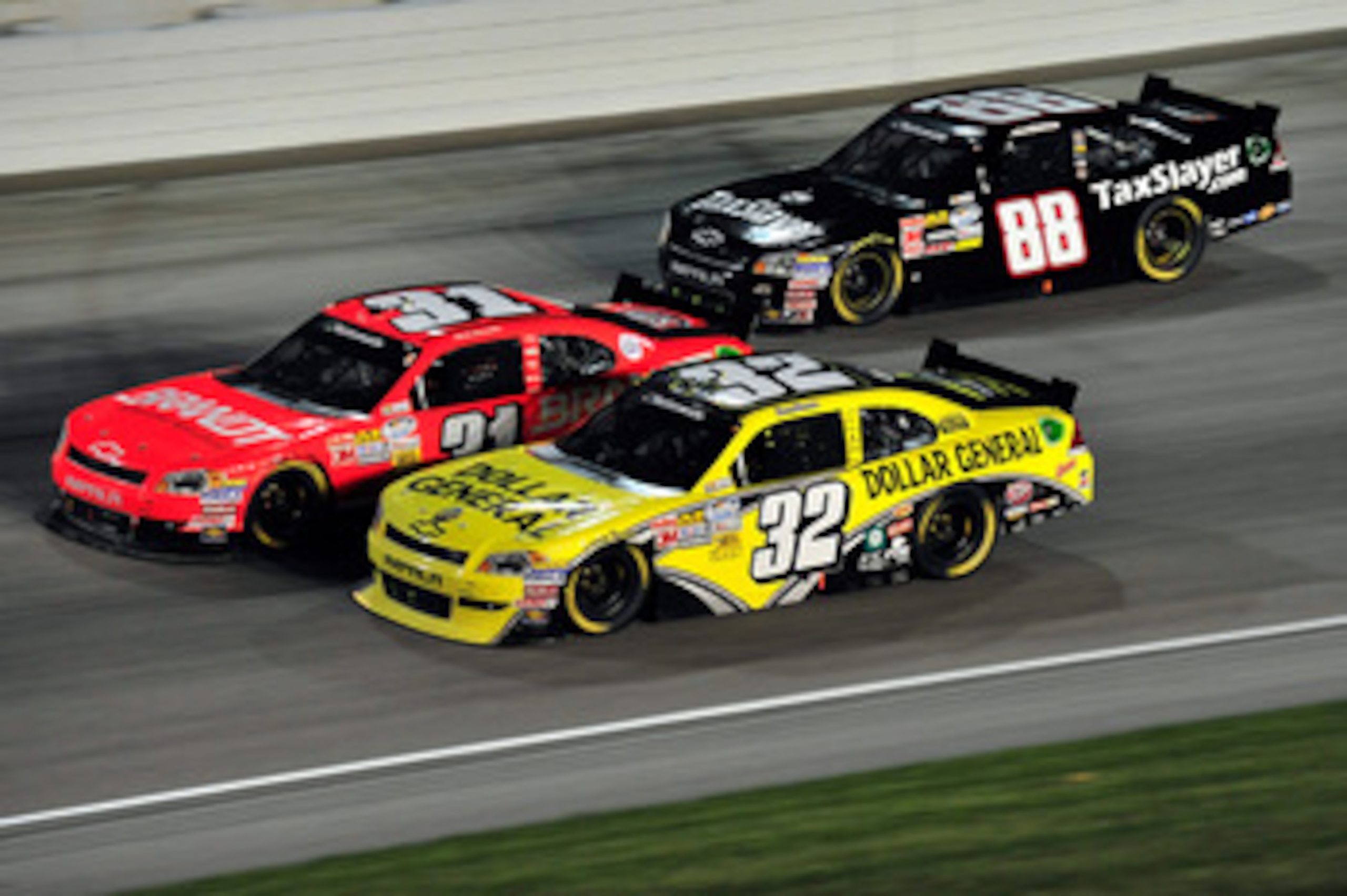 JOLIET, IL - JUNE 4: Reed Sorenson, driver of the #32 Dollar General Toyota, races Justin Allgaier, driver of the #31 Brandt Chevrolet, and Aric Almirola, driver of the #88 TaxSlayer.com Chevrolet, during the NASCAR Nationwide Series STP 300 at Chicagolan JOLIET, IL - JUNE 4: Reed Sorenson, driver of the #32 Dollar General Toyota, races Justin Allgaier, driver of the #31 Brandt Chevrolet, and Aric Almirola, driver of the #88 TaxSlayer.com Chevrolet, during the NASCAR Nationwide Series STP 300 at Chicagolan