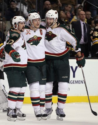 BOSTON, MA - JANUARY 06:  Mikko Koivu #9 of the Minnesota Wild is congratulated by teammates Cal Clutterbuck #22 and Brent Burns #8 after Koivu scored the empty net goal against the Boston Bruins on January 6, 2010 at the TD Garden in Boston, Massachusett