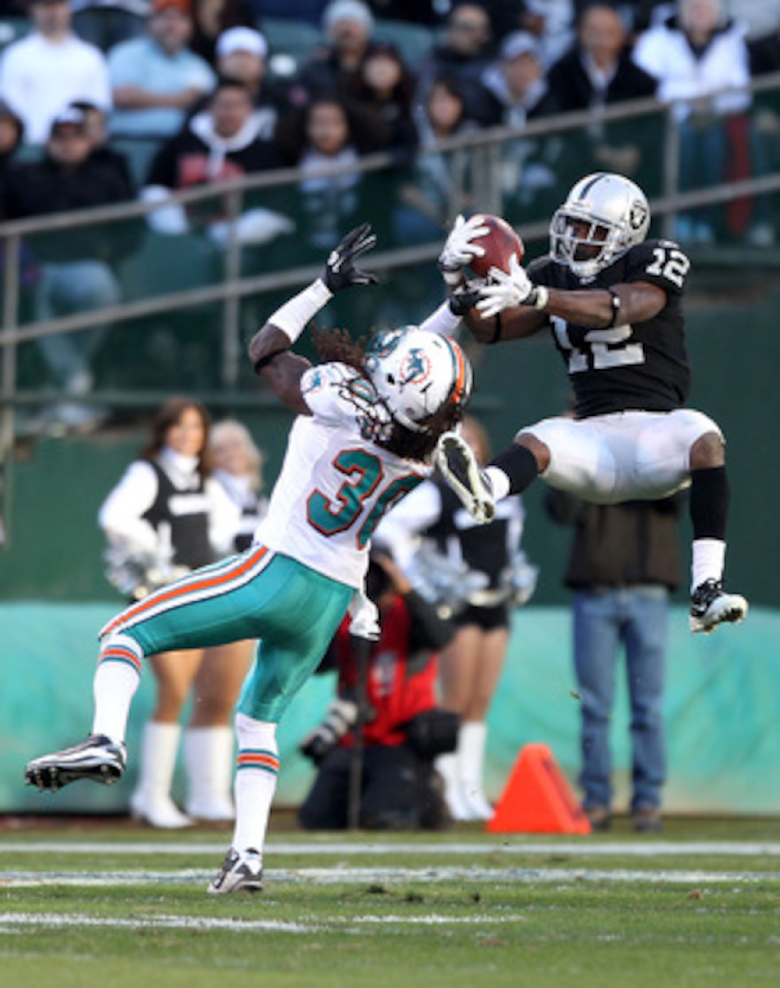 OAKLAND, CA - NOVEMBER 28:  Jacoby Ford #12 of the Oakland Raiders catches the ball while defended by Chris Clemons #30 of the Miami Dolphins at Oakland-Alameda County Coliseum on November 28, 2010 in Oakland, California.  (Photo by Ezra Shaw/Getty Images