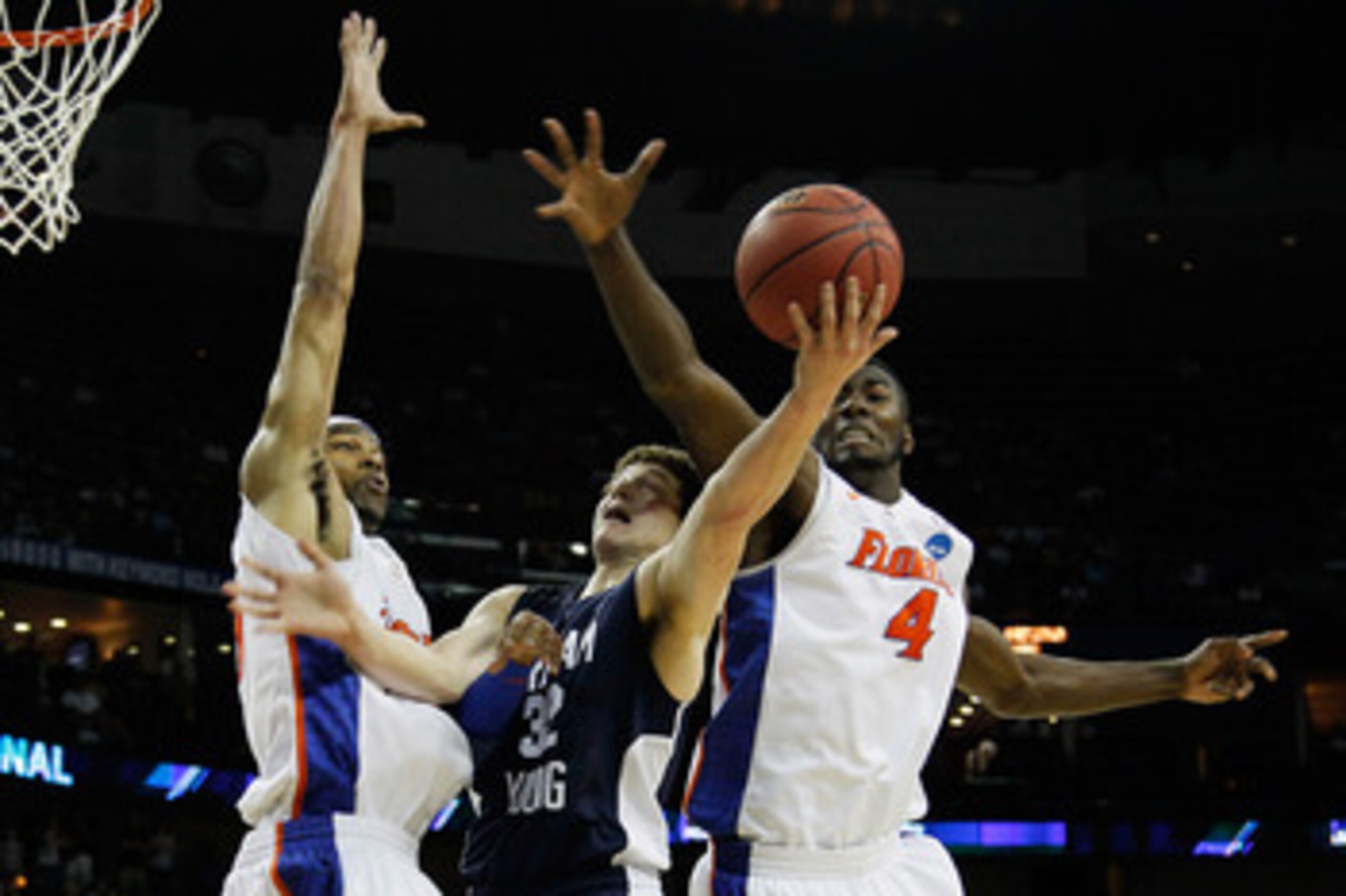 NEW ORLEANS, LA - MARCH 24:  Jimmer Fredette #32 of the Brigham Young Cougars goes up for a shot between Alex Tyus #23 and Patric Young #4 of the Florida Gators during the Southeast regional of the 2011 NCAA men's basketball tournament at New Orleans Aren