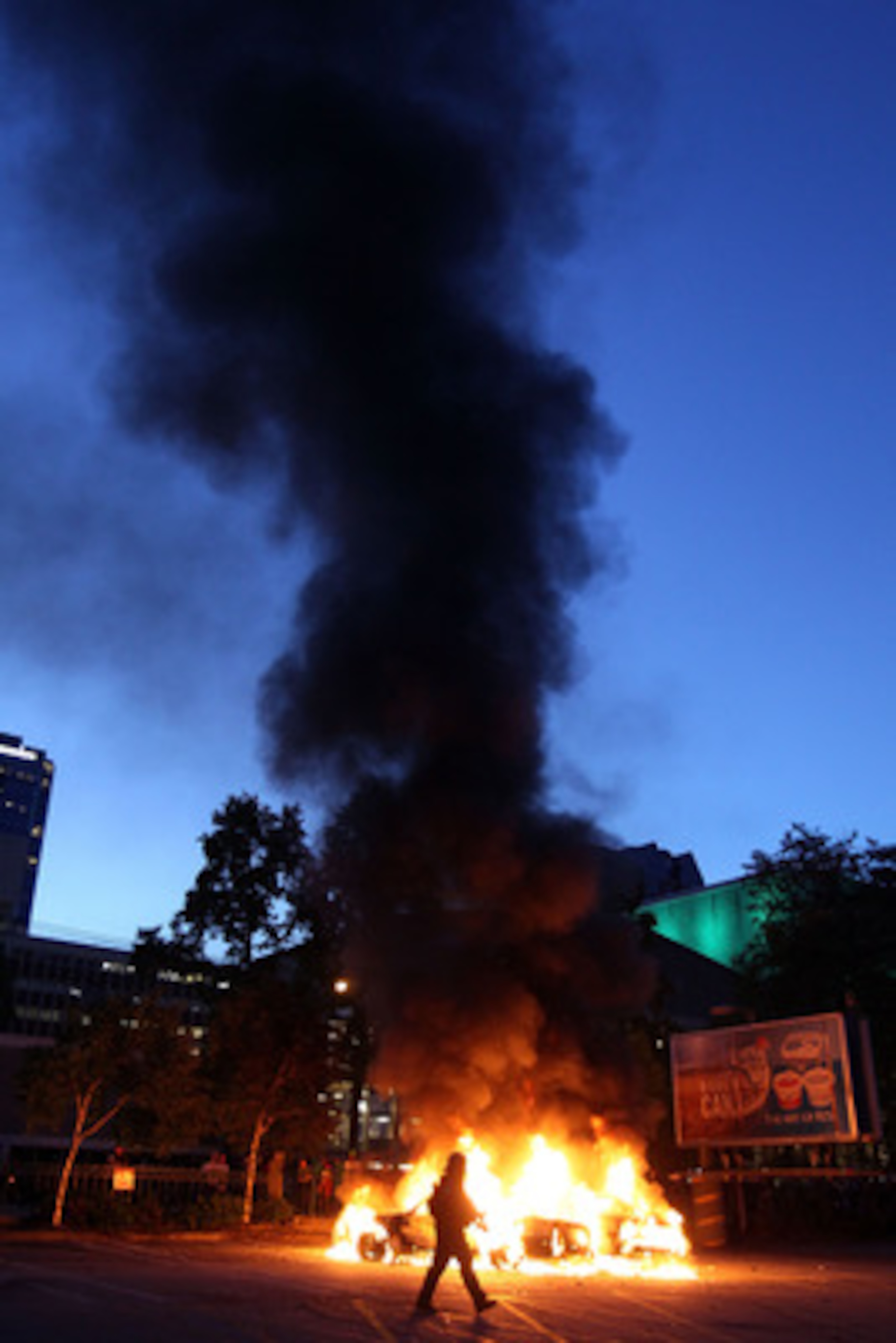VANCOUVER, BC - JUNE 15:  Riot police walk in front of two buring police cars on June 15, 2011 in Vancouver, Canada. Vancouver broke out in riots after their hockey team the Vancouver Canucks lost in Game Seven of the Stanley Cup Finals.  (Photo by Elsa/G