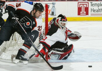 PHILADELPHIA - APRIL 10:  Keith Primeau #25 of the Philadelphia Flyers looks to control the puck in front of goalie Martin Brodeur #30 of the New Jersey Devils as the Flyers defeated the Devils 3-2 during game two of round one of the NHL Stanley Cup Playo