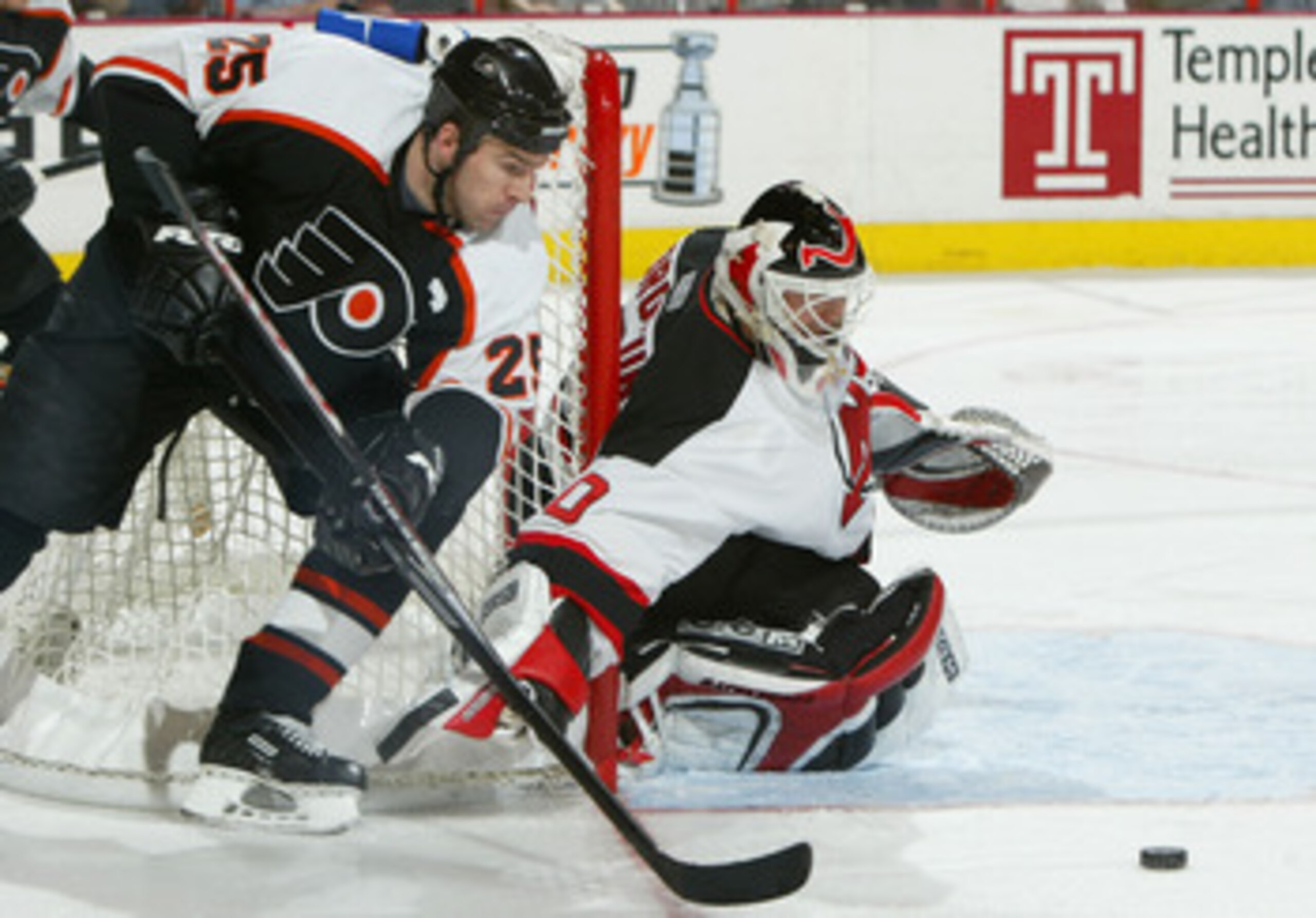PHILADELPHIA - APRIL 10:  Keith Primeau #25 of the Philadelphia Flyers looks to control the puck in front of goalie Martin Brodeur #30 of the New Jersey Devils as the Flyers defeated the Devils 3-2 during game two of round one of the NHL Stanley Cup Playo