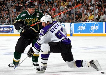 DALLAS - OCTOBER 5:  Center Mike Modano #9 of the Dallas Stars moves the puck past Jeremy Roenick #97 of the Los Angeles Kings on October 5, 2005 at the American Airlines Center in Dallas, Texas.  (Photo by Ronald Martinez/Getty Images)
