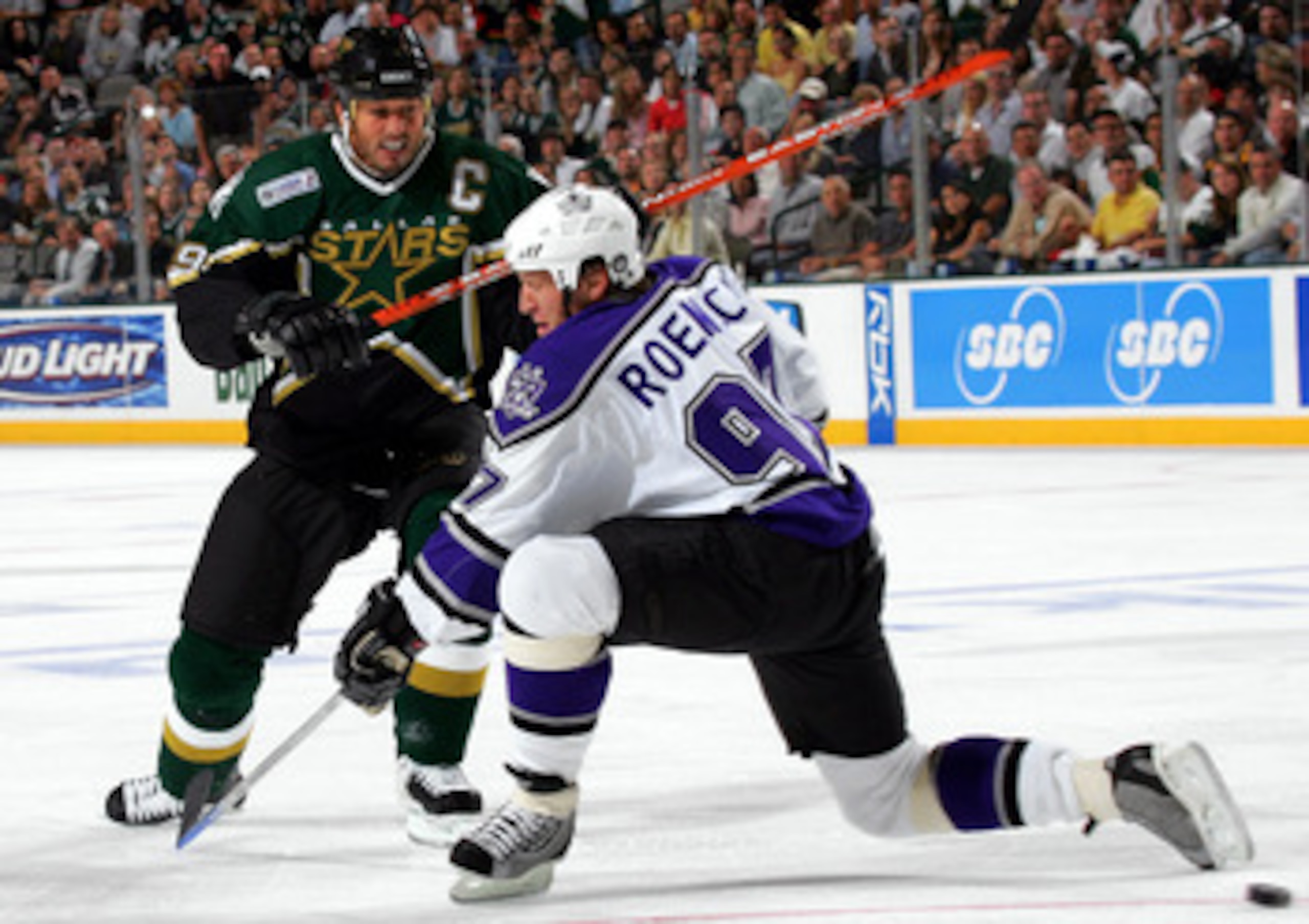 DALLAS - OCTOBER 5:  Center Mike Modano #9 of the Dallas Stars moves the puck past Jeremy Roenick #97 of the Los Angeles Kings on October 5, 2005 at the American Airlines Center in Dallas, Texas.  (Photo by Ronald Martinez/Getty Images)