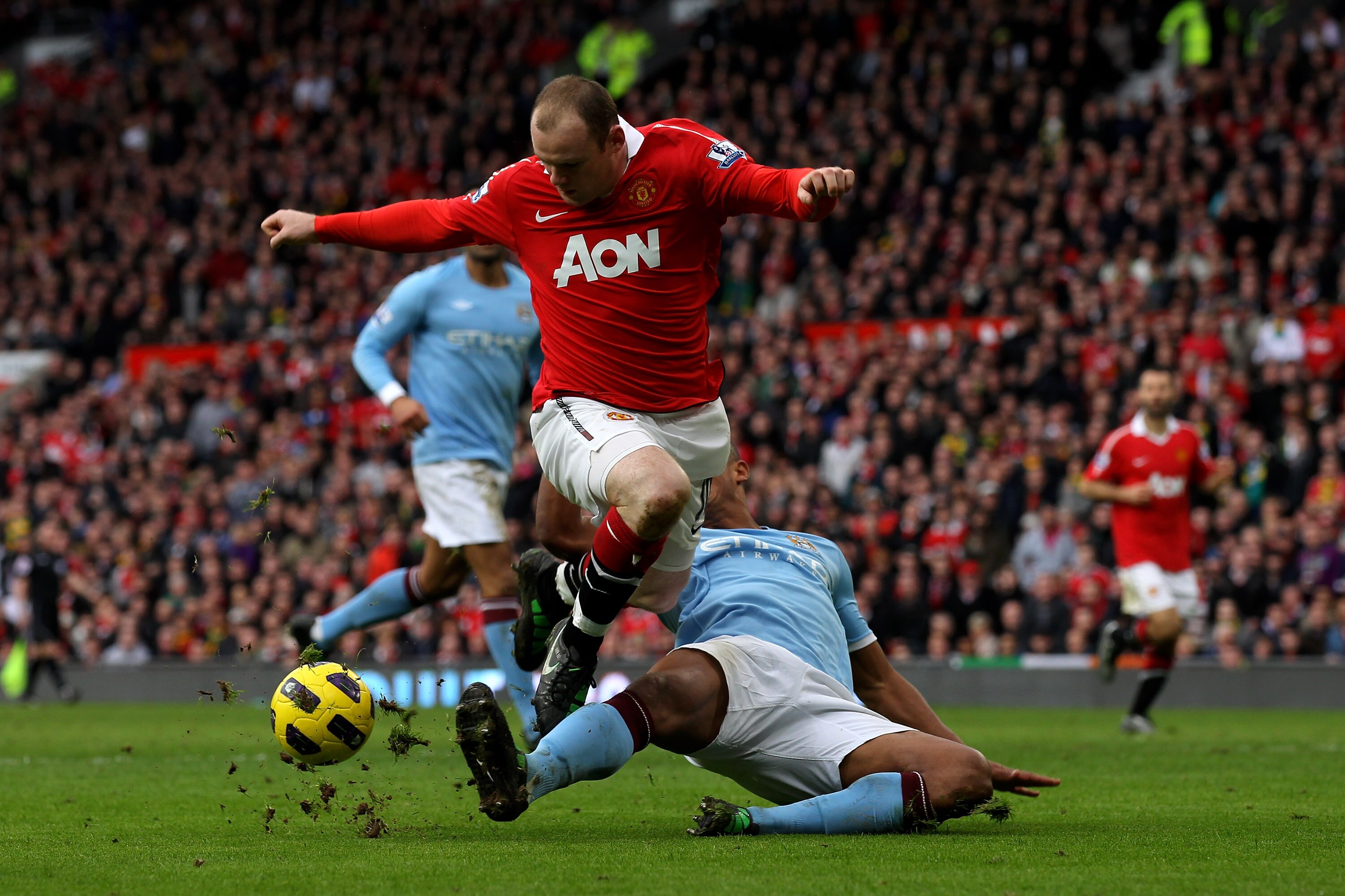 MANCHESTER, ENGLAND - FEBRUARY 12:  Wayne Rooney of Manchester United is tackled by Vincent Kompany of Manchester City during the Barclays Premier League match between Manchester United and Manchester City at Old Trafford on February 12, 2011 in Mancheste