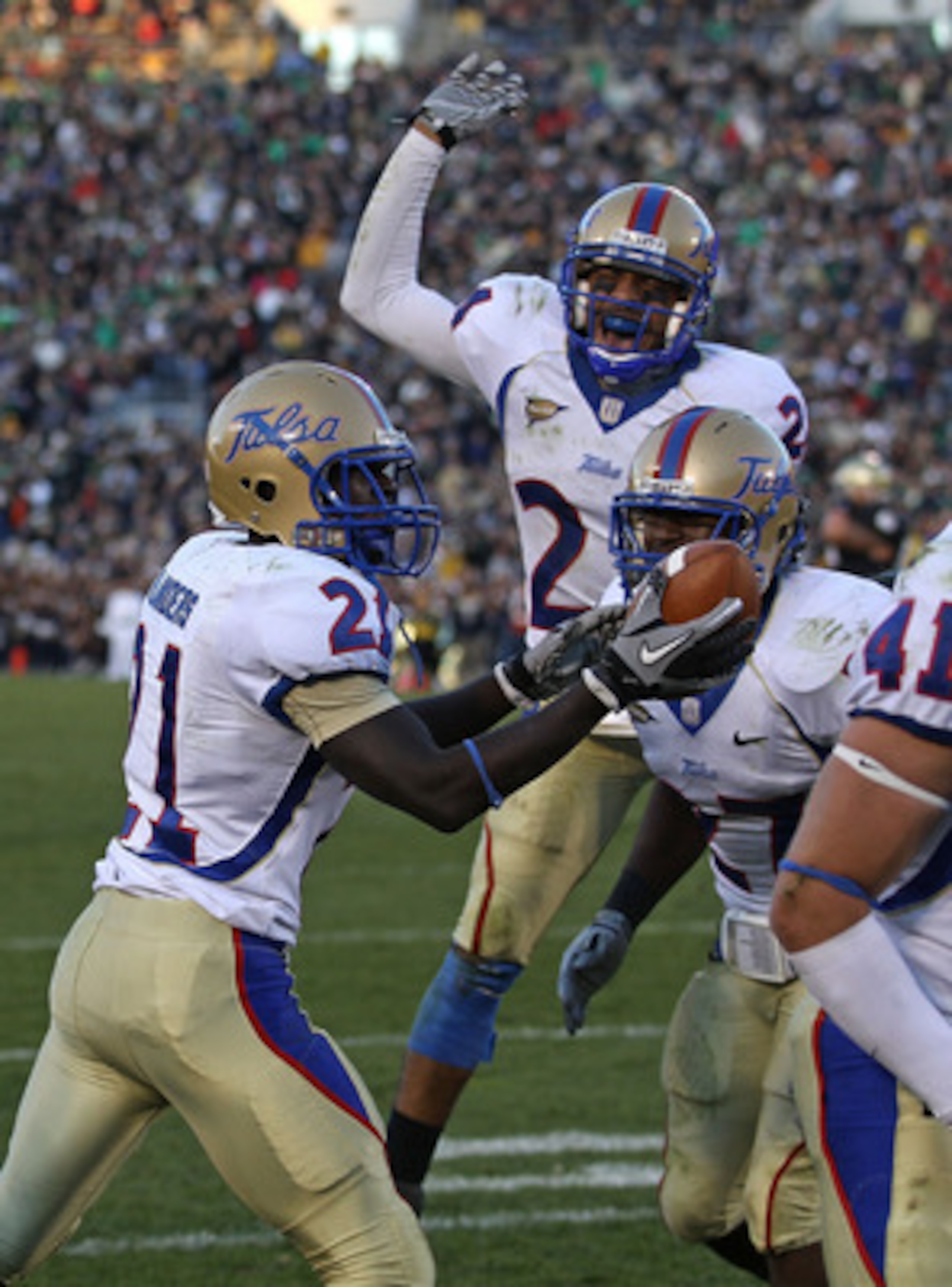 SOUTH BEND, IN - OCTOBER 30: John Flanders #21 of the Tulsa Golden Hurricane holds the ball after intercepting a pass in the end zone against the Notre Dame Fighting Irish as teammates Charles Davis #24 (center) and DeWitt Jennings #27 join the celebratio