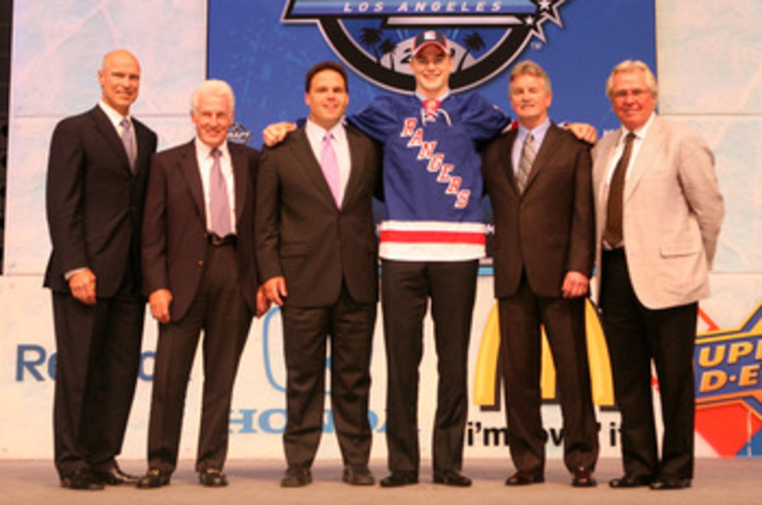 LOS ANGELES, CA - JUNE 25:  Dylan McIlrath, drafted tenth overall by the New York Rangers, poses on stage with team personnel during the 2010 NHL Entry Draft at Staples Center on June 25, 2010 in Los Angeles, California.  (Photo by Bruce Bennett/Getty Ima