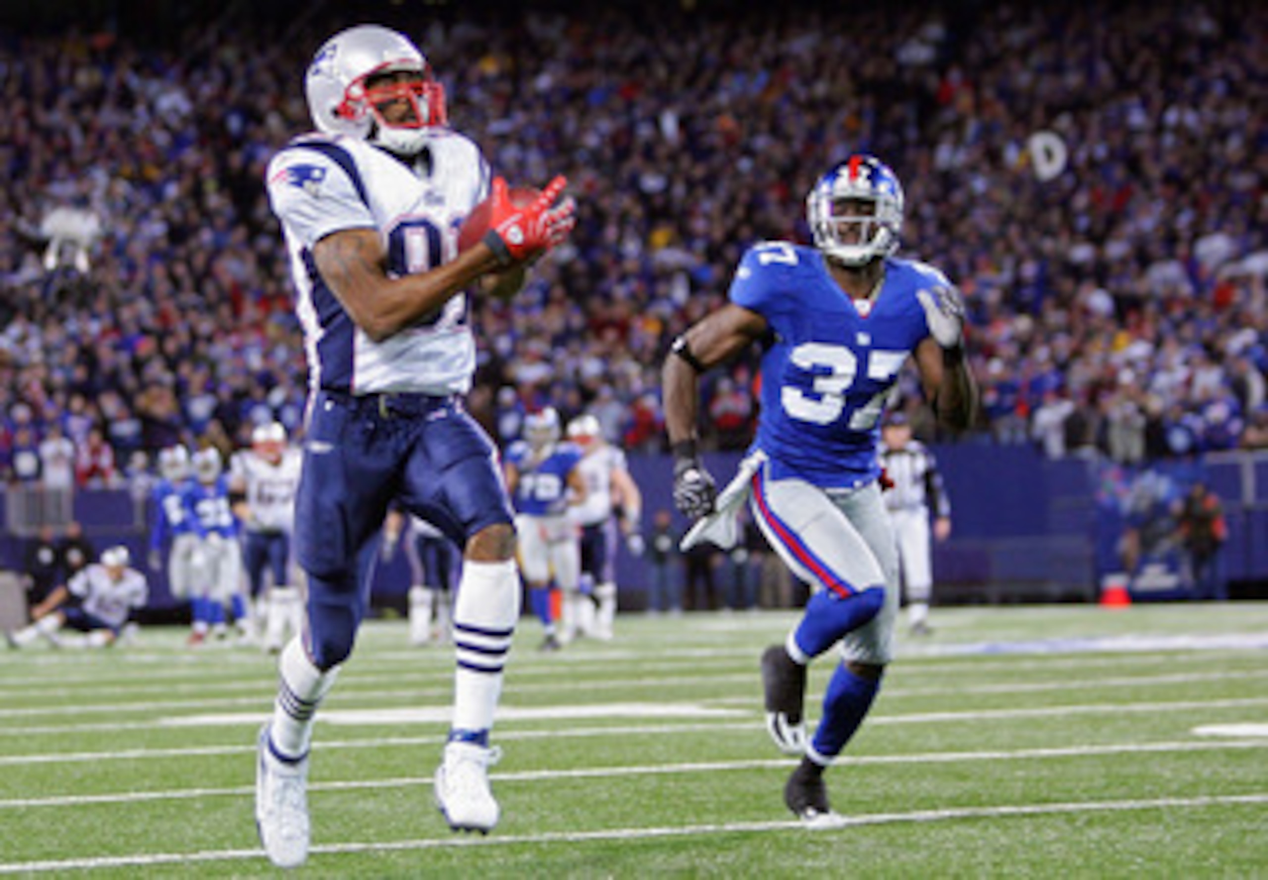 EAST RUTHERFORD, NJ - DECEMBER 29:  Randy Moss  #81 of the New England Patriots runs after a catch for his 23rd touchdown of the season breaking the all time season high for touchdowns in a season against James Butler #37 of the New York Giants on Decembe