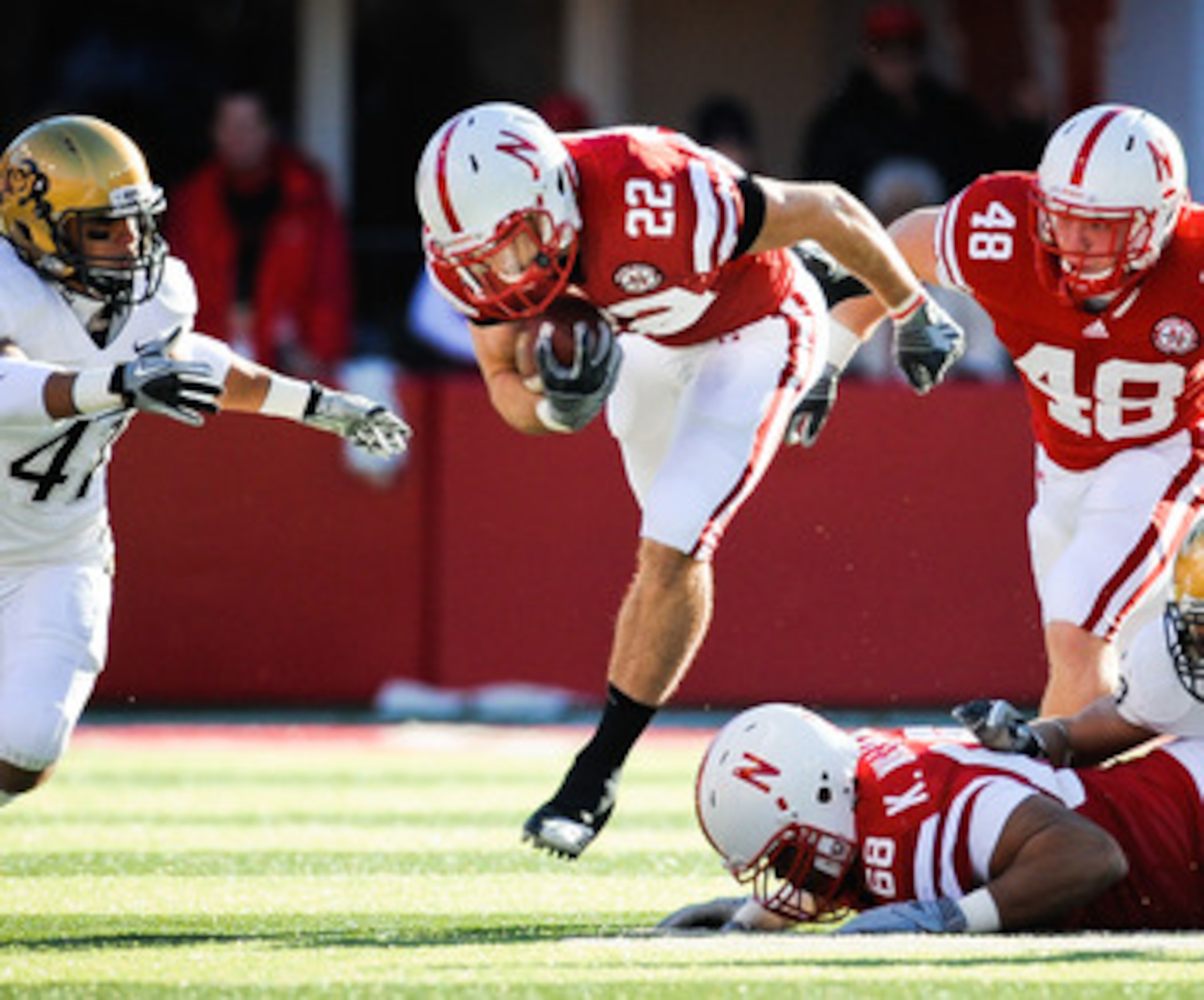 LINCOLN, NE - NOVEMBER 26: Rex Burkhead #22 of the Nebraska Cornhuskers leaps over teammate Keith Williams #68 and is helped by Tyler Legate #48 and Kyler Reed #25 of the Nebraska Cornhuskers during their game against the Colorado Buffaloes at Memorial St