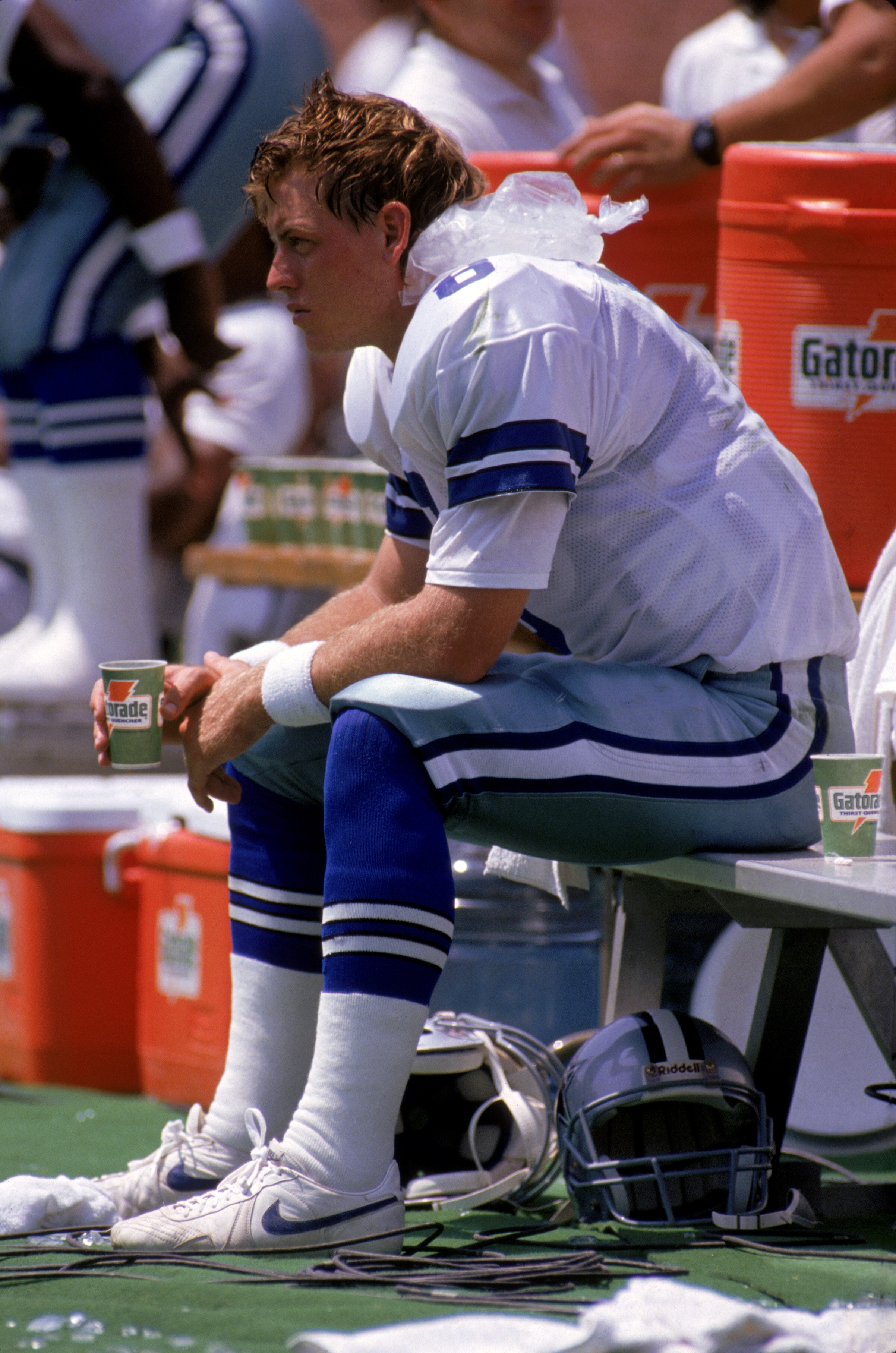 OAKLAND, CA - AUGUST 18:  Quarterback Troy Aikman #8 of the Dallas Cowboys ices the back of his neck and drinks a cup of Gatorade as he sits on the bench to recover from a concussion during a preseason game against the Oakland Raiders at Oakland/Alameda C