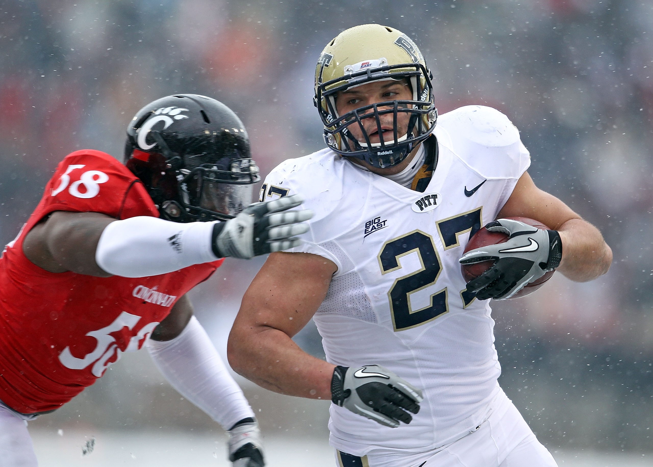 CINCINNATI, OH - DECEMBER 04:  Henry Hynoski #27 of the Pittsburgh Panthers runs with the ball while defended by Brandon Mills #58 of the Cincinnati Bearcats during the Big East Conference game against at Nippert Stadium on December 4, 2010 in Cincinnati,