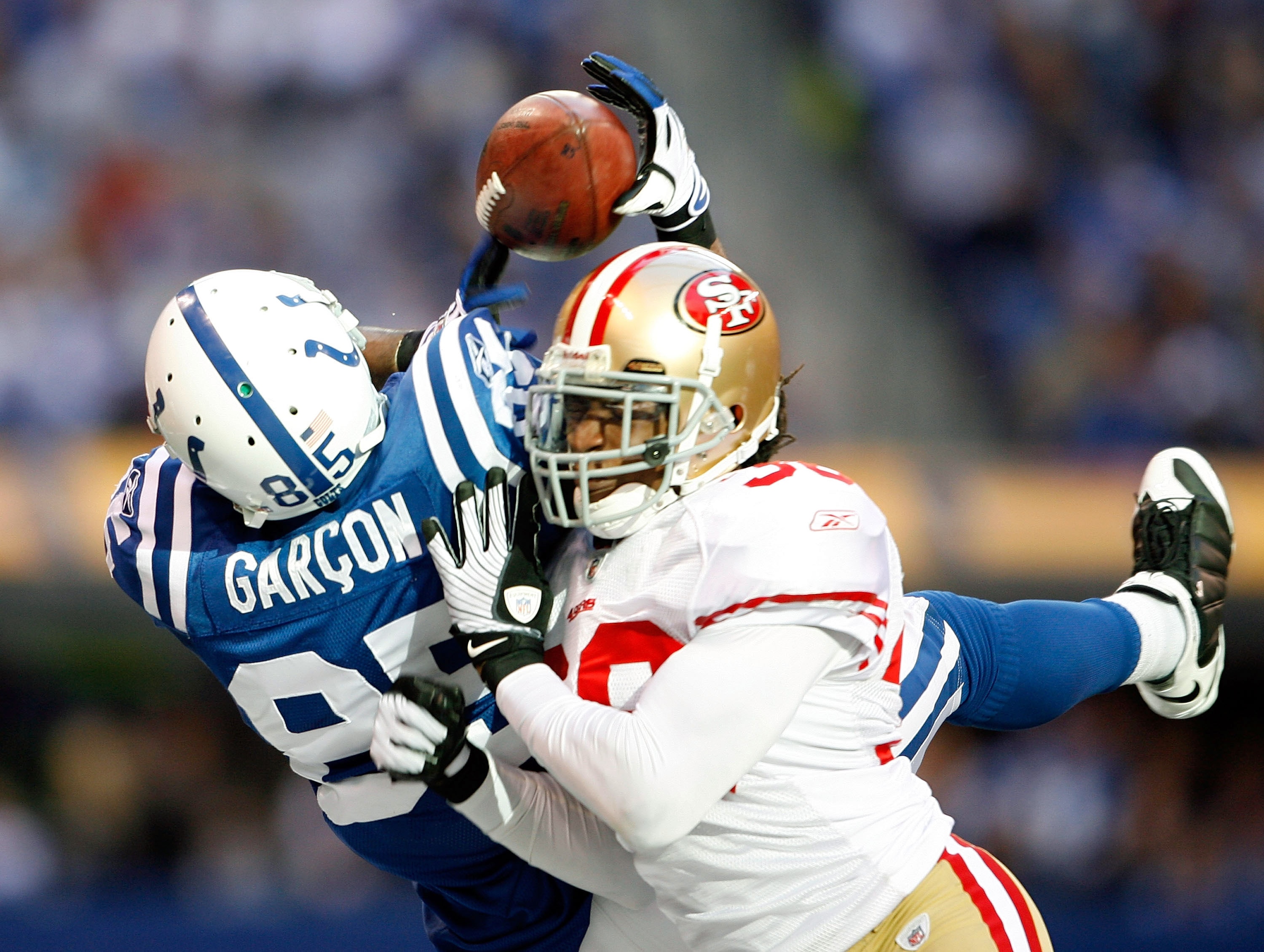 INDIANAPOLIS - NOVEMBER 01:  Pierre Garcon #85 of the Indianapolis Colts reaches for the ball as he is hit by Dashon Goldson #38 of the San Francisco 49ers during the NFL game at Lucas Oil Stadium on November 1, 2009 in Indianapolis, Indiana. The Colts wo