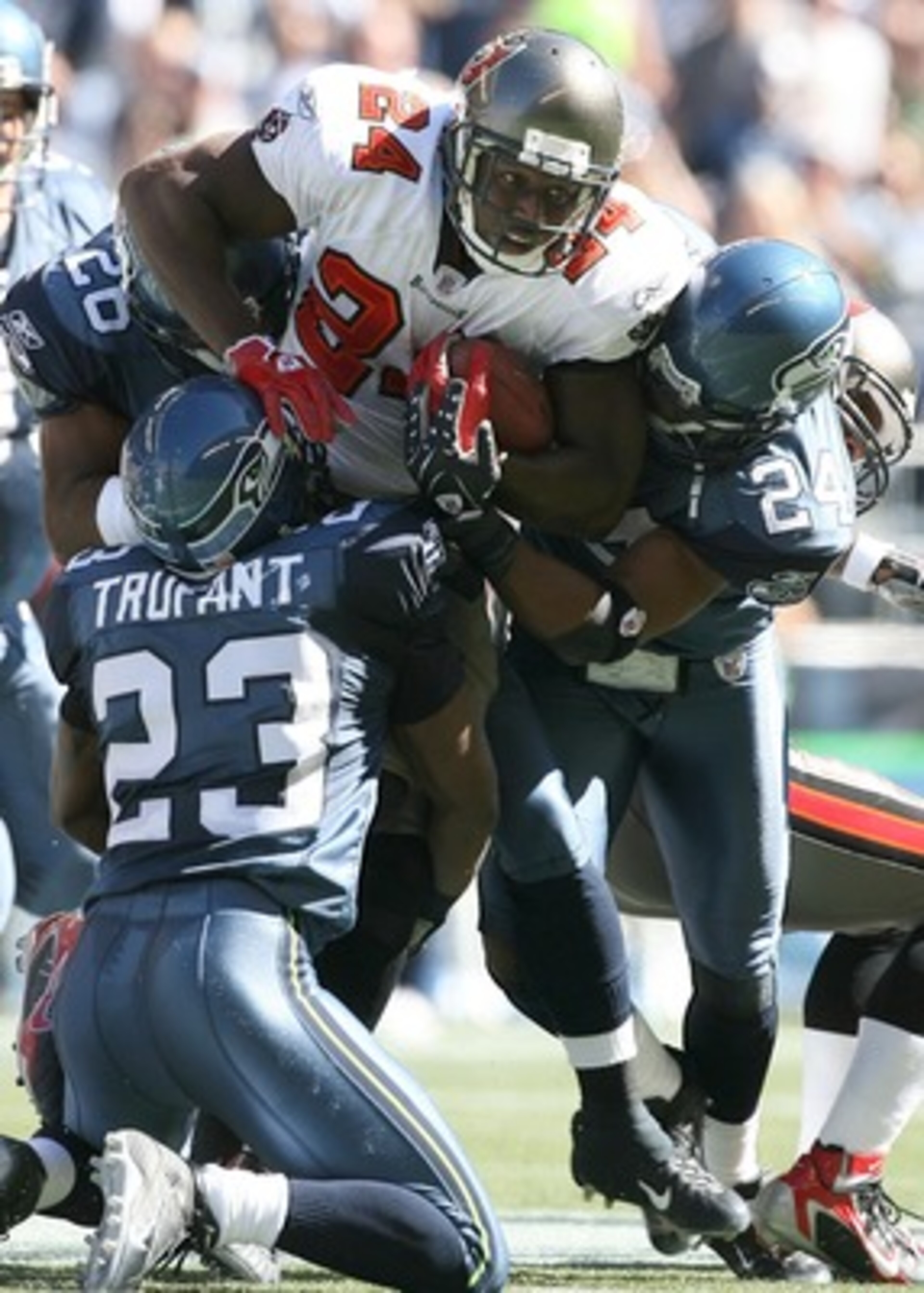 SEATTLE - SEPTEMBER 09:  Running back  Carnell Williams #24 of the Tampa Bay Buccaneers rushes against Marcus Trufant #23 and Deon Grant #24 of the Seattle Seahawks at Qwest Field on September 9, 2007 in Seattle, Washington. The Seahawks defeated the Bucc