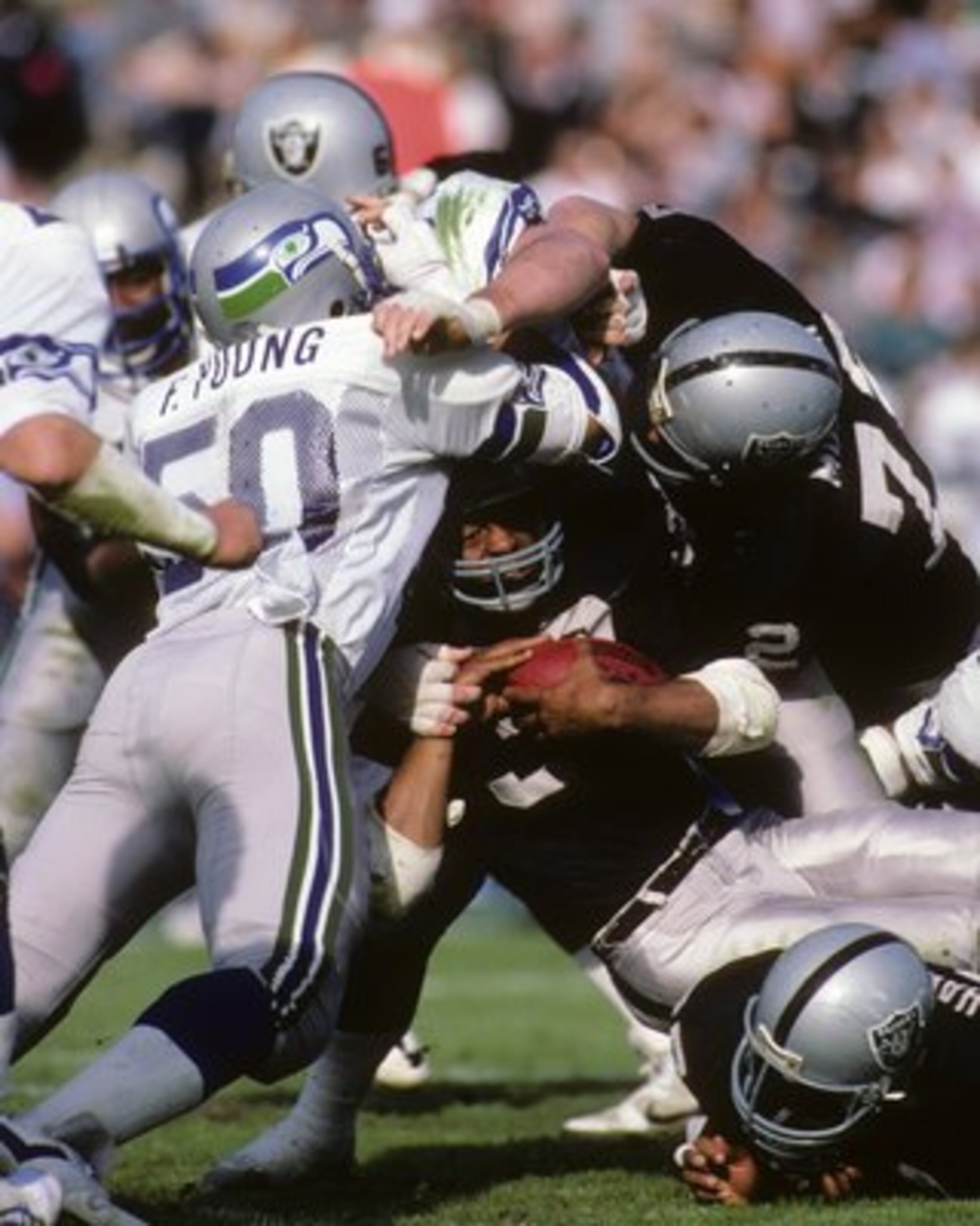 LOS ANGELES, CA - DECEMBER 15: Linebacker Fredd Young #50 of the Seattle Seahawks tackles Los Angeles Raiders running back Marcus Allen #32 during the game at Los Angeles Memorial Coliseum on December 15, 1985 in Los Angeles, California. The Raiders won LOS ANGELES, CA - DECEMBER 15: Linebacker Fredd Young #50 of the Seattle Seahawks tackles Los Angeles Raiders running back Marcus Allen #32 during the game at Los Angeles Memorial Coliseum on December 15, 1985 in Los Angeles, California. The Raiders won