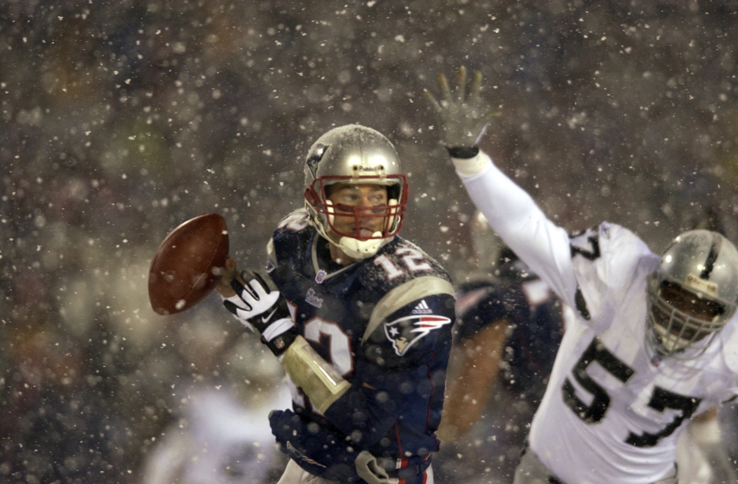 19 Jan 2002:  Quarterback Tom Brady #12 of the New England Patriots scrambles against the defense of Rod Coleman #57 of the Oakland Raiders during the AFC playoff game at Foxboro Stadium in Foxboro, Massachuesetts. The Patriots came from behind to win 16-