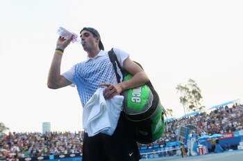 MELBOURNE, AUSTRALIA - JANUARY 22:  John Isner of the United States of America drinks a bottle of water as he leaves the court after losing to Marin Cilic of Croatia during their third round match on day six of the 2011 Australian Open at Melbourne Park o