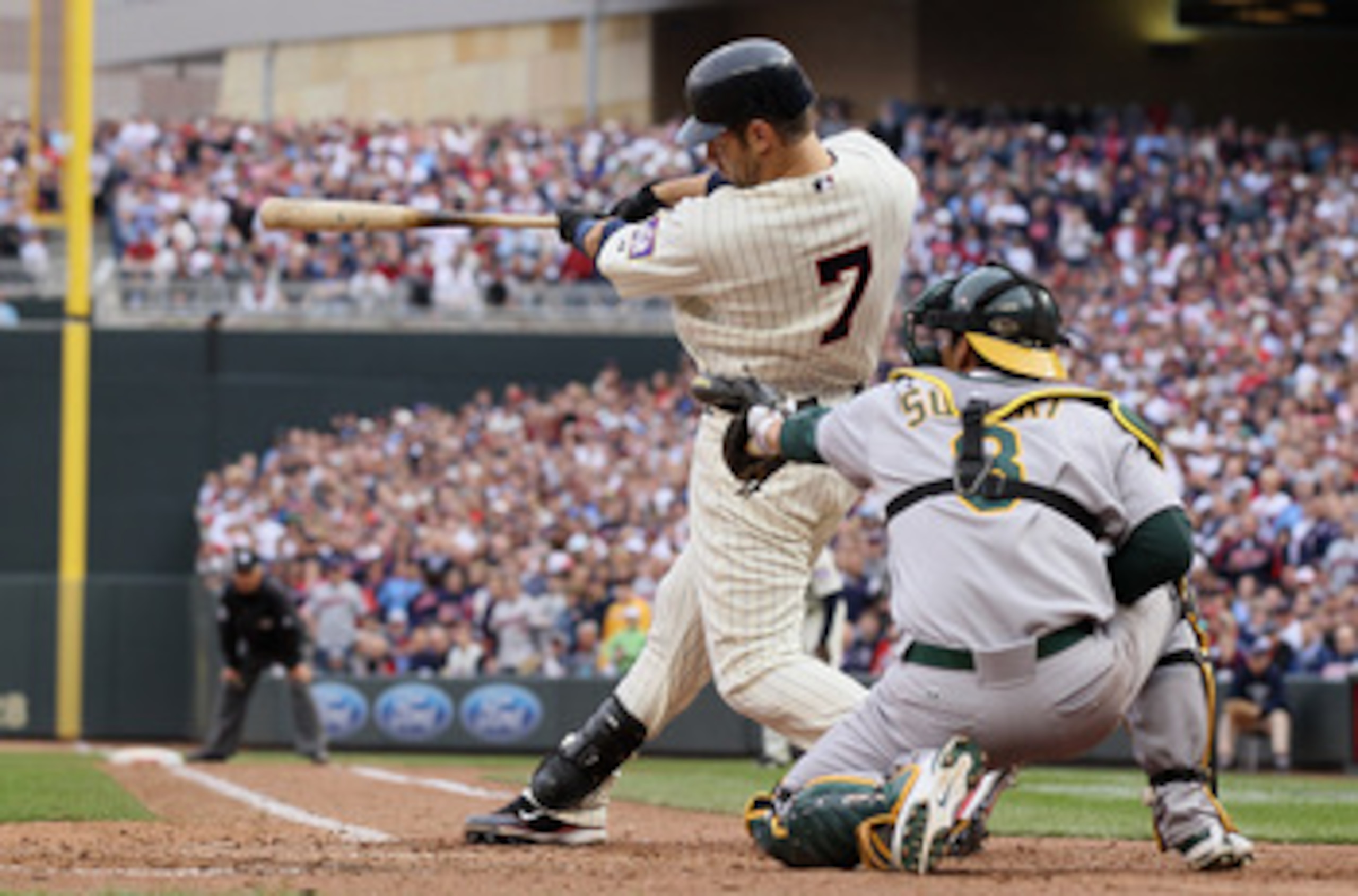 MINNEAPOLIS, MN - APRIL 08:  Joe Mauer #7 of the Minnesota Twins drives in the winning run as Kurt Suzuki #8 of the Oakland Athletics catches during Opening Day on April 8, 2011 at Target Field in Minneapolis, Minnesota. The Minnesota Twins defeated the O