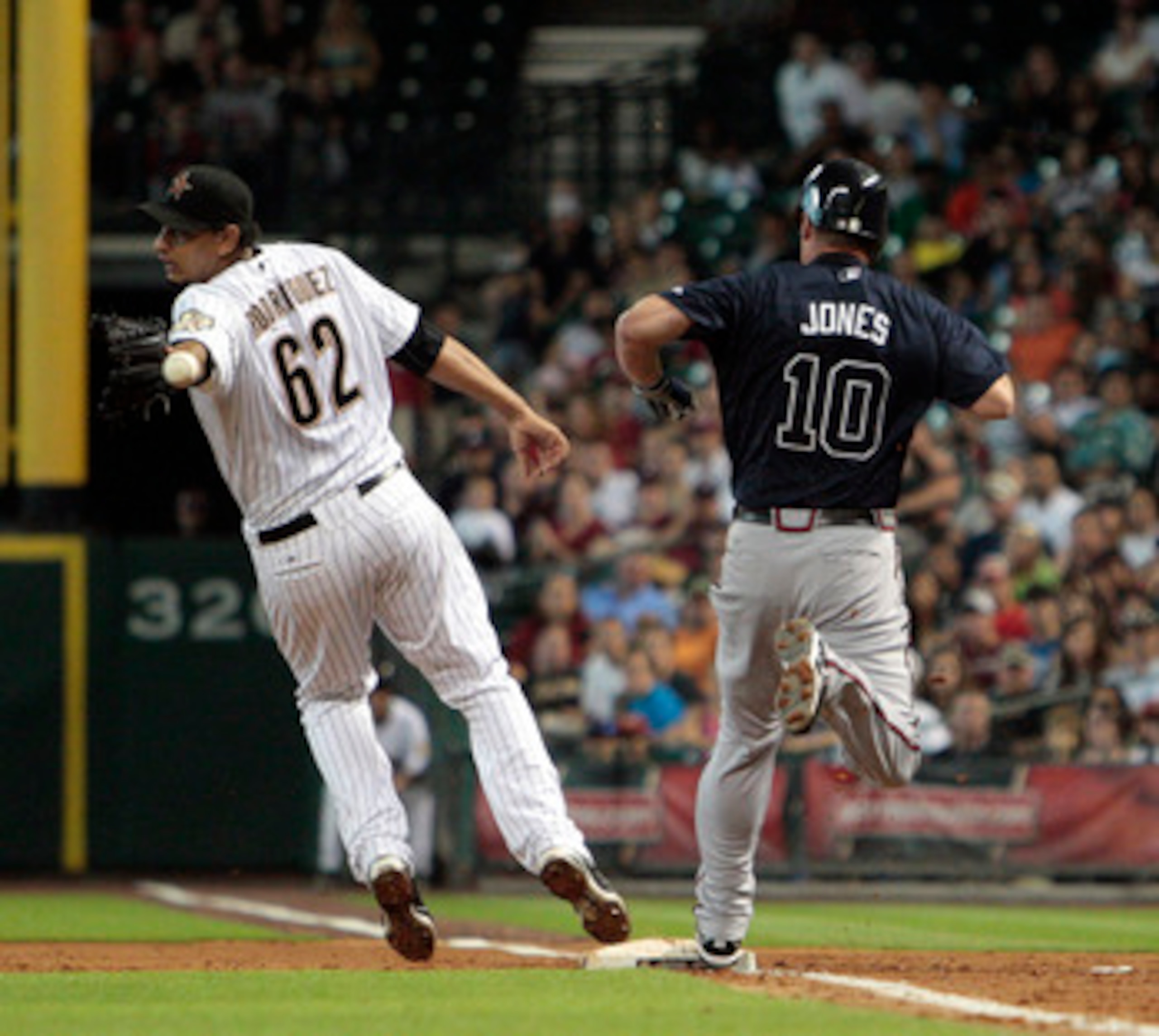 HOUSTON - JUNE 10:  Pitcher Aneury Rodriguez #62 of the Houston Astros can't handle the throw as Chipper Jones #10 of the Atlanta Braves beats it to the bag at Minute Maid Park on June 10, 2011 in Houston, Texas.  (Photo by Bob Levey/Getty Images)