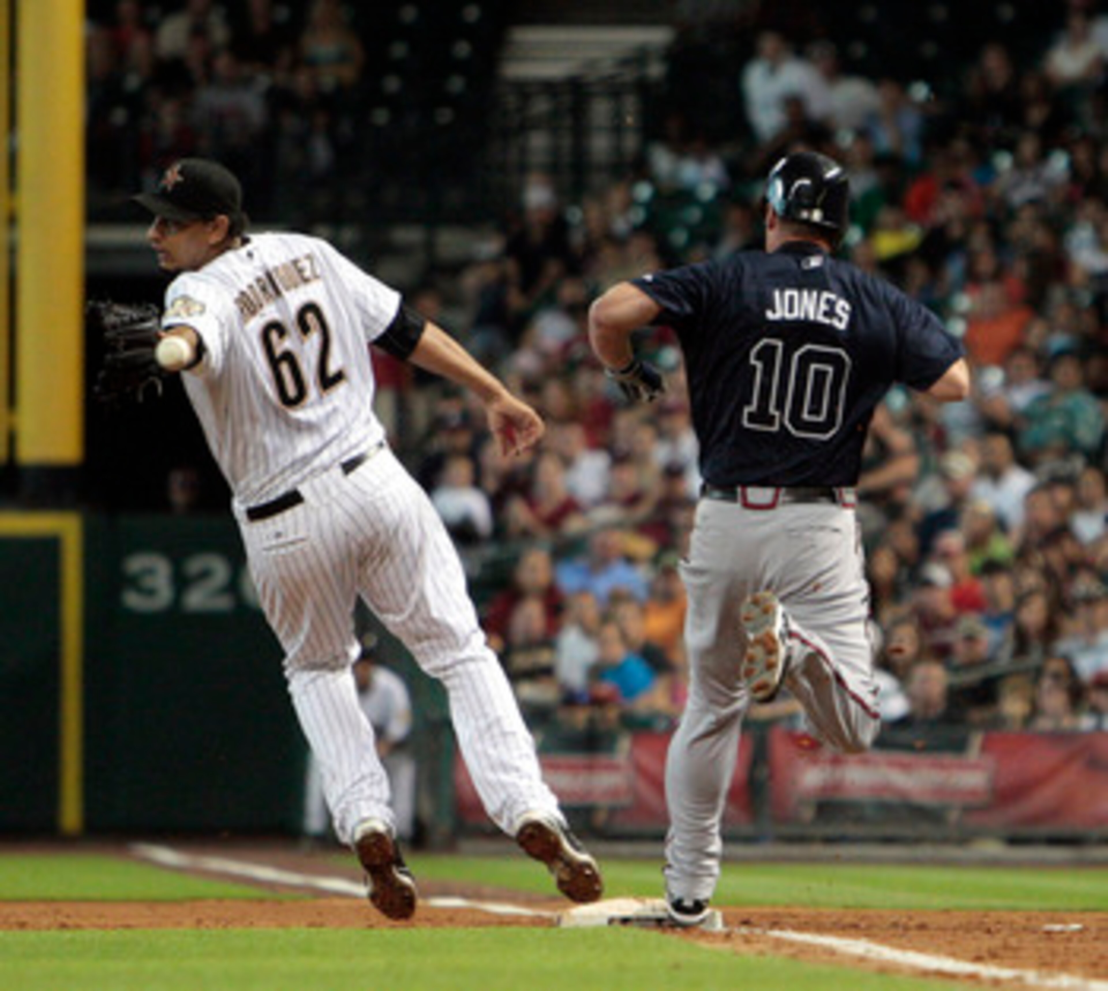 HOUSTON - JUNE 10:  Pitcher Aneury Rodriguez #62 of the Houston Astros can't handle the throw as Chipper Jones #10 of the Atlanta Braves beats it to the bag at Minute Maid Park on June 10, 2011 in Houston, Texas.  (Photo by Bob Levey/Getty Images)