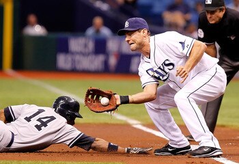 ST. PETERSBURG, FL - JULY 18:  Infielder Casey Kotchman #11 of the Tampa Bay Rays takes the throw at first as Curtis Granderson #14 of the New York Yankees gets back safely during the game at Tropicana Field on July 18, 2011 in St. Petersburg, Florida.  (