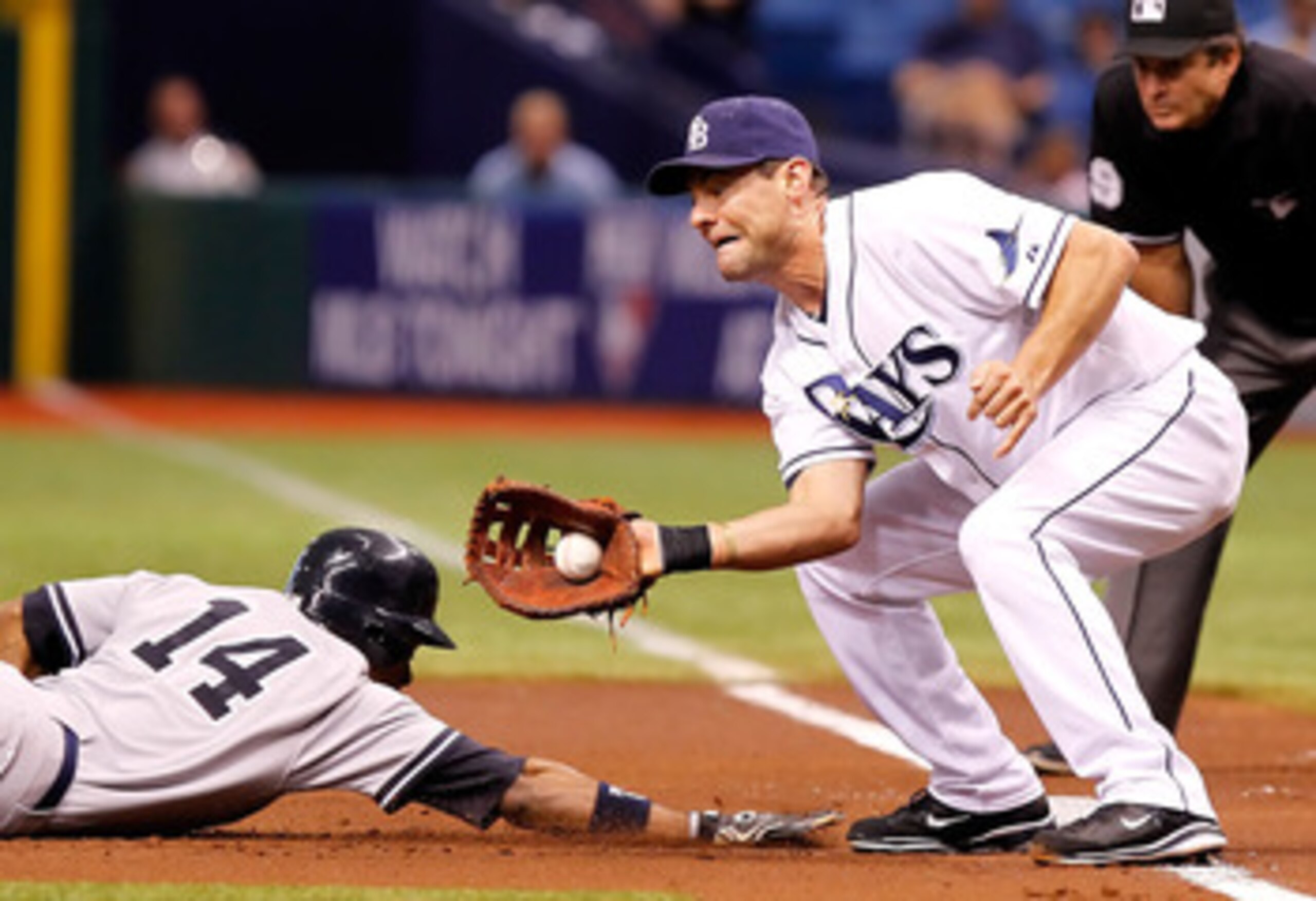 ST. PETERSBURG, FL - JULY 18:  Infielder Casey Kotchman #11 of the Tampa Bay Rays takes the throw at first as Curtis Granderson #14 of the New York Yankees gets back safely during the game at Tropicana Field on July 18, 2011 in St. Petersburg, Florida.  (