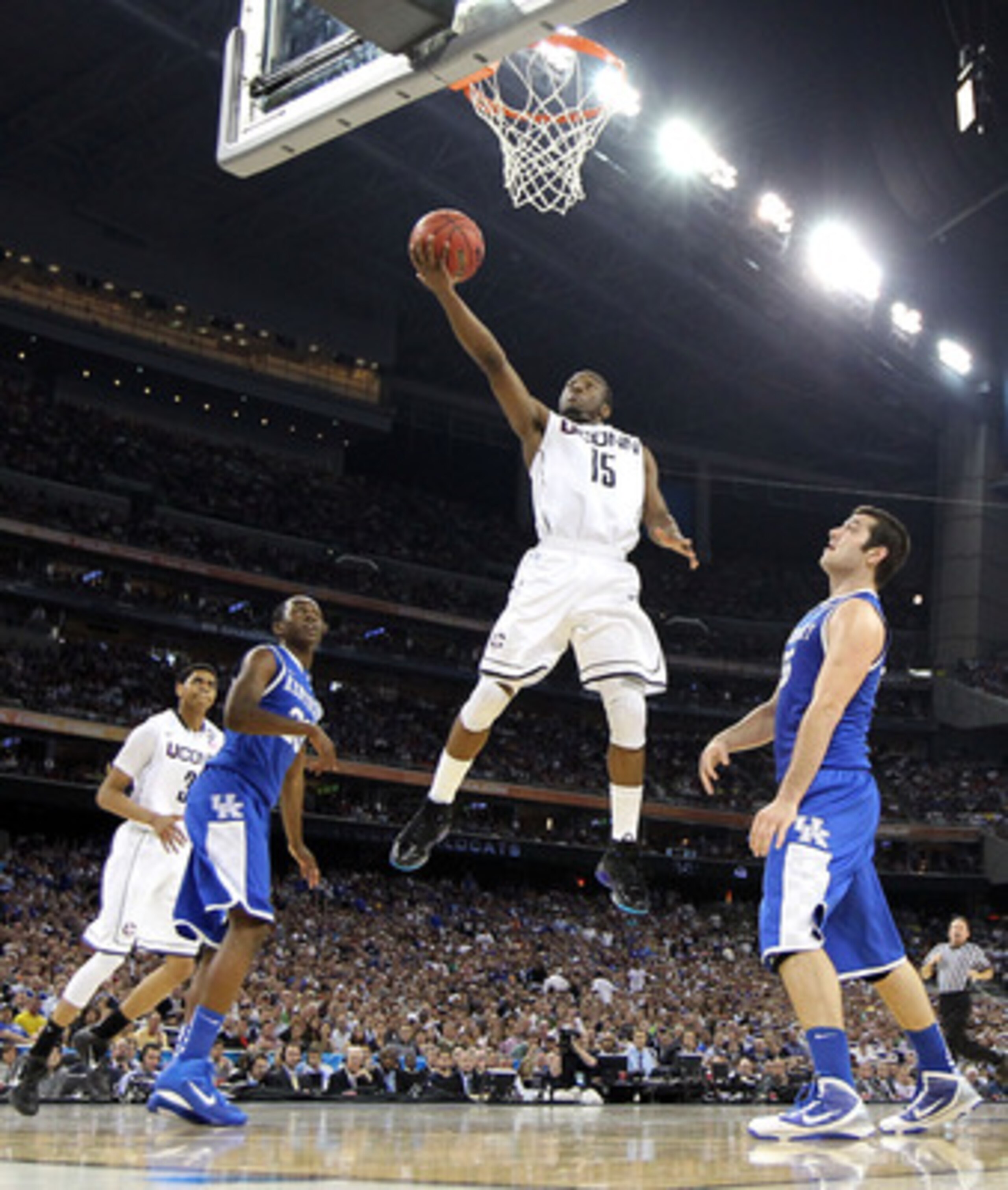 HOUSTON, TX - APRIL 02:  Kemba Walker #15 of the Connecticut Huskies goes to the hoop past Josh Harrellson #55 and Doron Lamb #20 of the Kentucky Wildcats during the National Semifinal game of the 2011 NCAA Division I Men's Basketball Championship at Reli