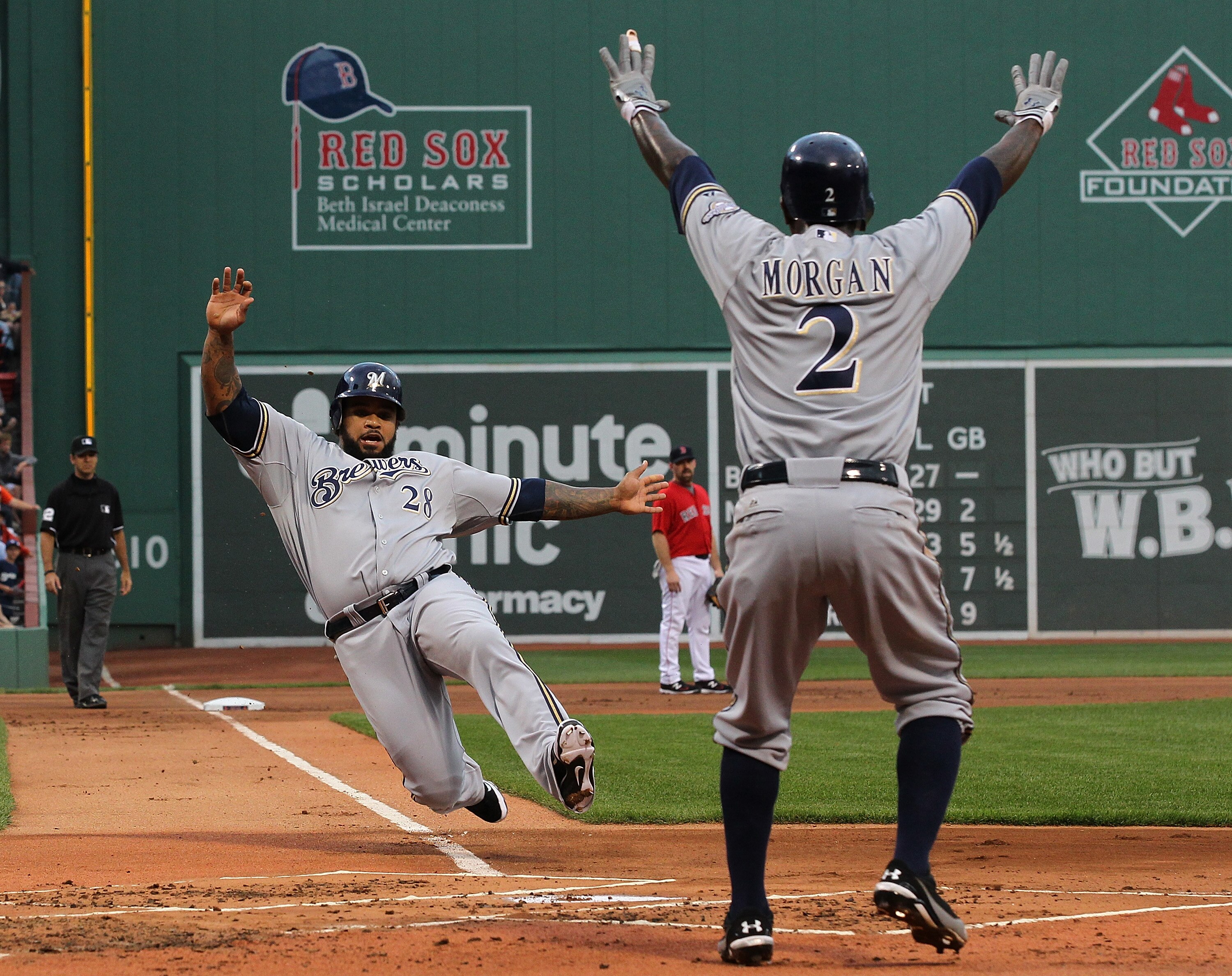 BOSTON, MA  - JUNE 17:  Prince Fielder #28  of the Milwaukee Brewers slides safely into home under the direction of teammate Nyjer Morgan #2 against the Boston Red Sox at Fenway Park on June 17, 2011 in Boston, Massachusetts.  (Photo by Jim Rogash/Getty I
