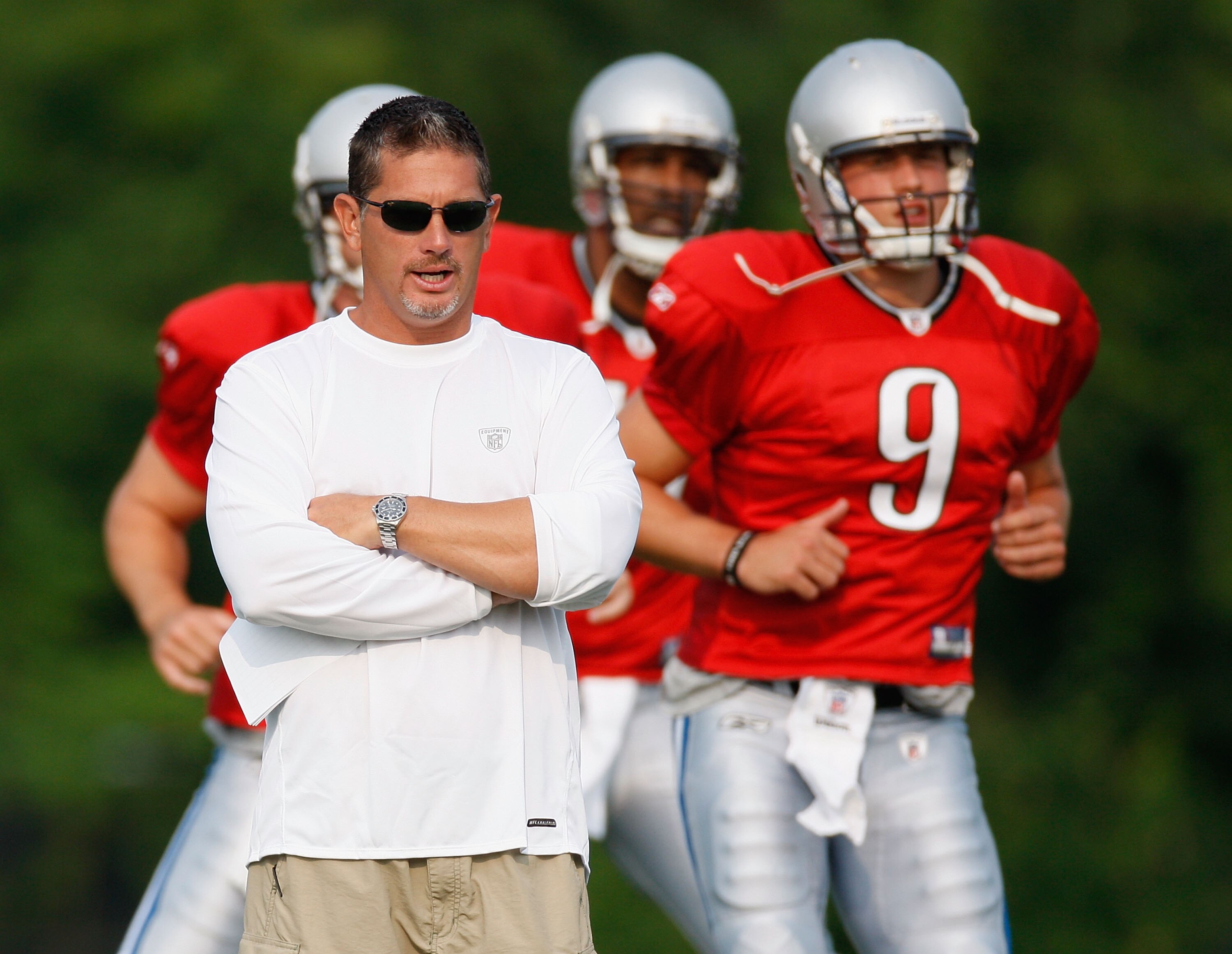 ALLEN PARK, MI - AUGUST 04:  Head coach Jim Schwartz looks on while Matthew Stafford #9 and Daunte Culpepper #11 warm up during training camp at the Detroit Lions Headquarters and Training Facility on August 4, 2009 in Allen Park, Michigan.  (Photo by Gre