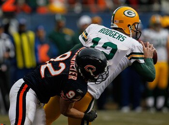 CHICAGO - DECEMBER 13: Aaron Rodgers #12 of the Green Bay Packers tosses the ball as he is brought down by Hunter Hillenmeyer #92 of the Chicago Bears at Soldier Field on December 13, 2009 in Chicago, Illinois. The Packers defeated the Bears 21-14. (Photo