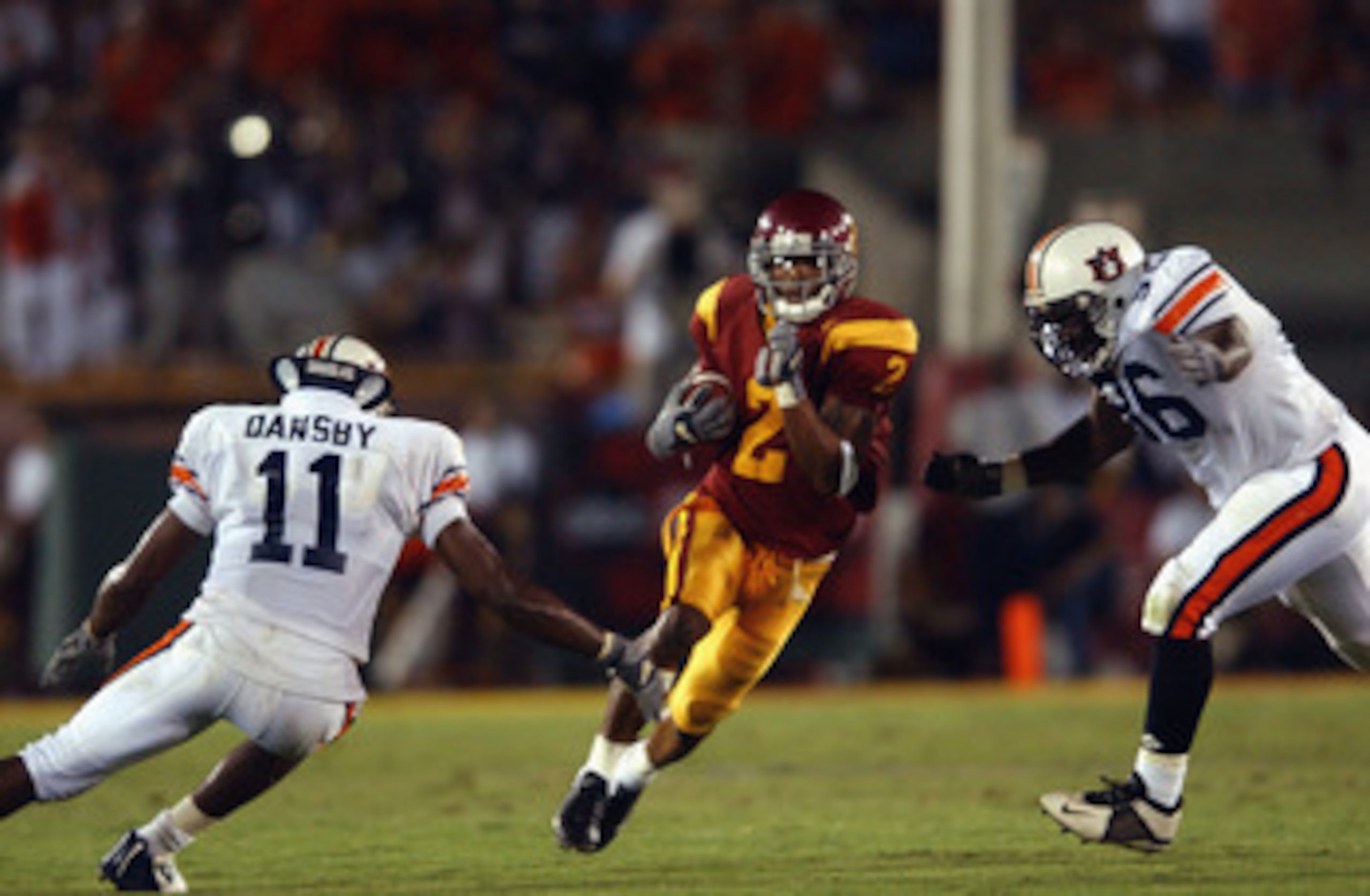 LOS ANGELES - SEPTEMBER 2:  Wide receiver Kareem Kelly #2 of the USC Trojans runs between nose guard Wayne Dickens and linebacker Karlos Dansby #11 of the Auburn Tigers at the Los Angeles Coliseum on September 2, 2002 in Los Angeles, California. USC defea
