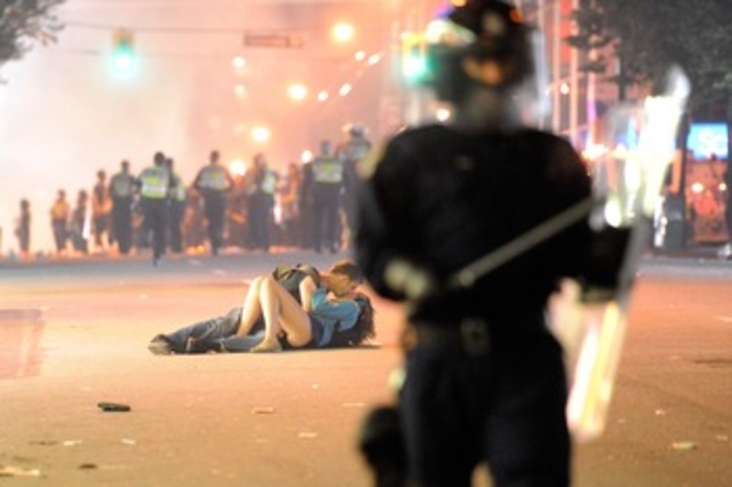 VANCOUVER, BC - JUNE 15:  Riot police walk in the street as a couple kiss on June 15, 2011 in Vancouver, Canada. Vancouver broke out in riots after their hockey team the Vancouver Canucks lost in Game Seven of the Stanley Cup Finals.  (Photo by Rich Lam/G