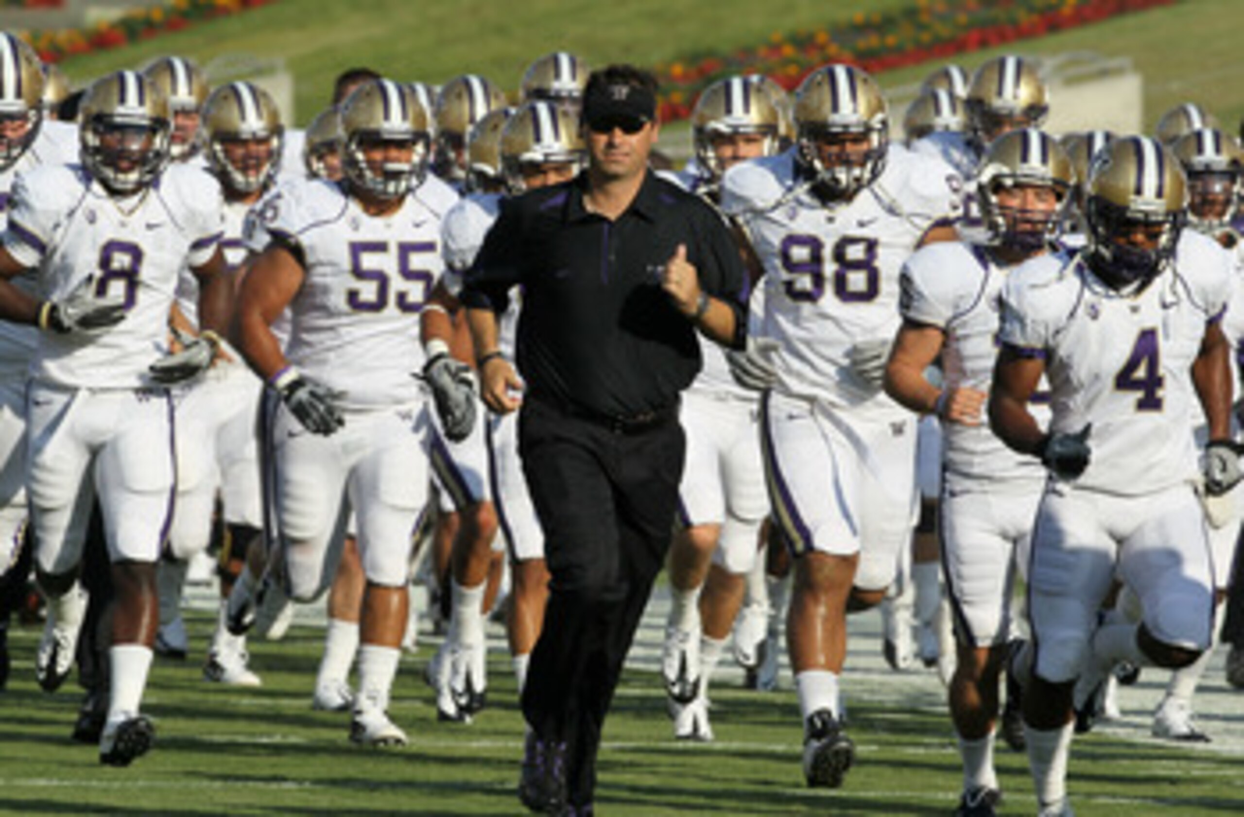LOS ANGELES - OCTOBER 2:   Head coach Steve Sarkisian of the Washington Huskies runs off the field with his team after warmups for th game with the USC Trojans at the Los Angeles Memorial Coliseum on October 2, 2010 in Los Angeles, California.    (Photo b