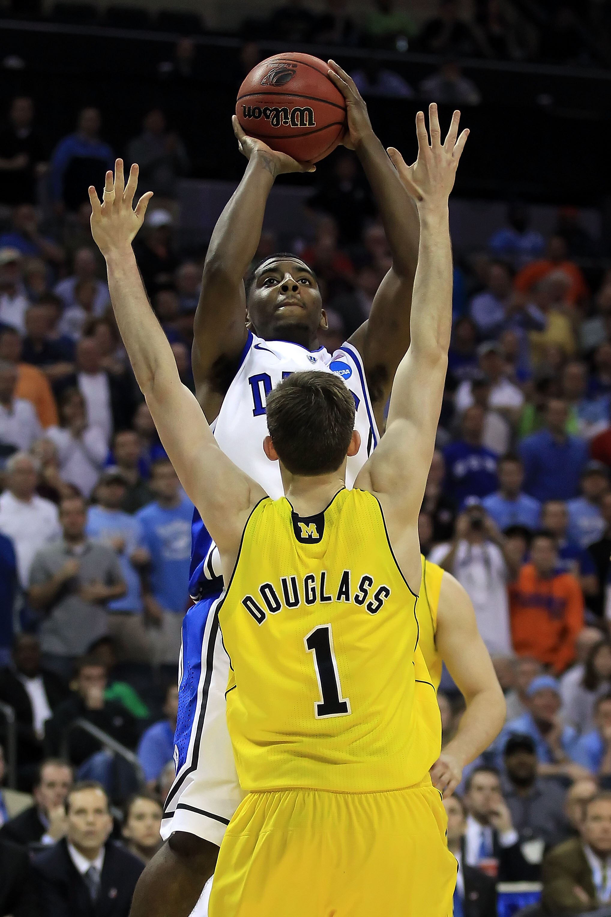 CHARLOTTE, NC - MARCH 20:  Kyrie Irving #1 of the Duke Blue Devils makes the eventual game-winning basket late in the second half while shooting over Stu Douglass #1 of the Michigan Wolverines during the third round of the 2011 NCAA men's basketball tourn