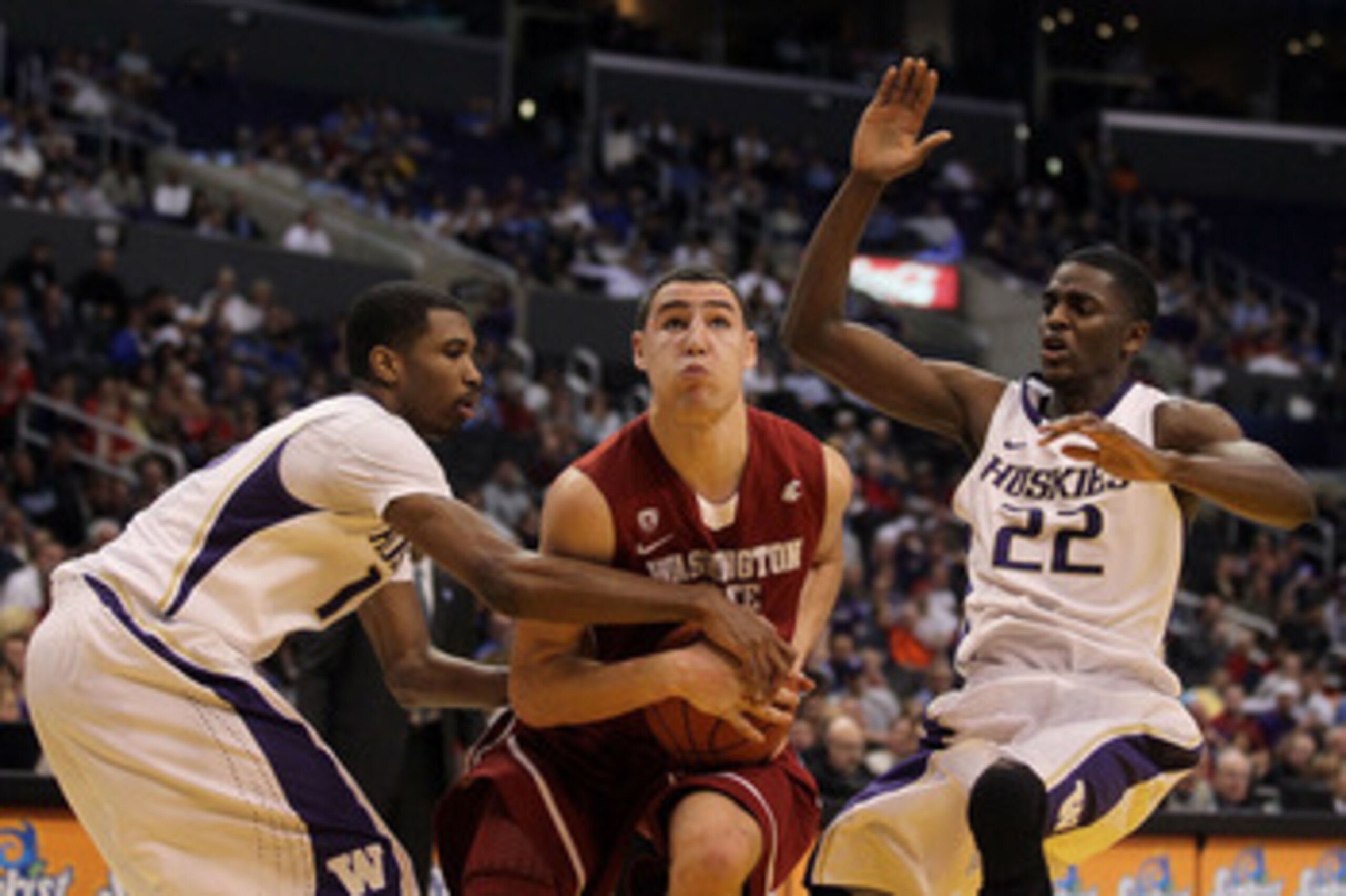 LOS ANGELES, CA - MARCH 10:  Klay Thompson #1 of the Washington State Cougars drives between Scott Suggs #15 and Justin Holiday #22 of the Washington Huskies in the first half in the quarterfinals of the 2011 Pacific Life Pac-10 Men's Basketball Tournamen