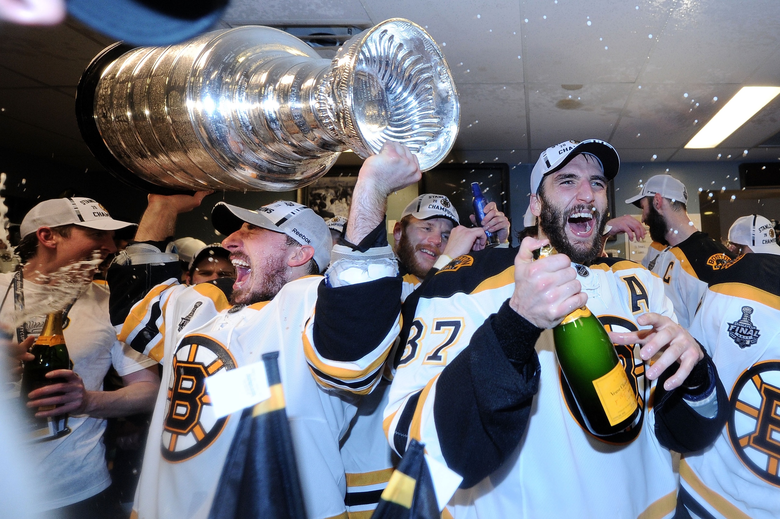 VANCOUVER, BC - JUNE 15:  Brad Marchand #63 and Patrice Bergeron #37 of the Boston Bruins celebrate with the Stanley Cup in th locker room after Game Seven of the 2011 NHL Stanley Cup Final at Rogers Arena on June 15, 2011 in Vancouver, British Columbia,