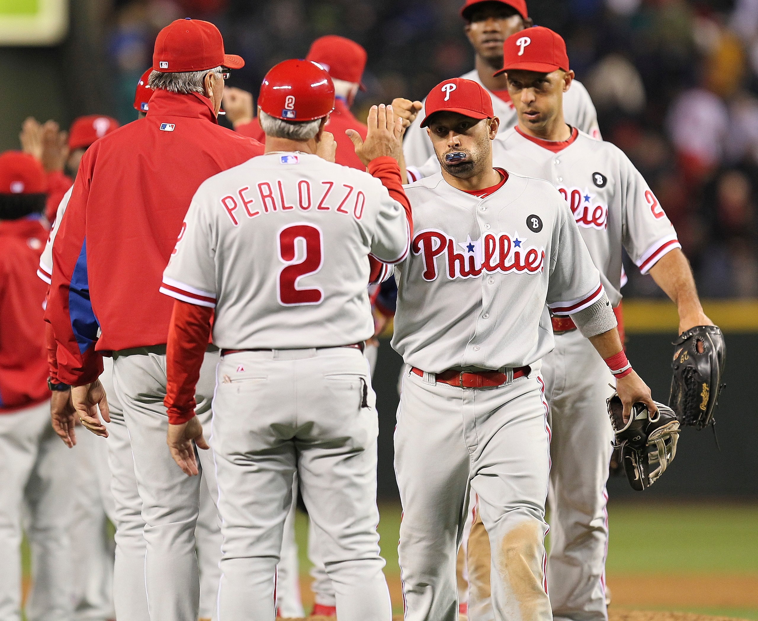 SEATTLE - JUNE 18:  Shane Victorino #8 of the Philadelphia Phillies is congratulated by first base coach Sam Perlozzo #2 after defeating the Seattle Mariners 5-1 at Safeco Field on June 18, 2011 in Seattle, Washington. (Photo by Otto Greule Jr/Getty Image