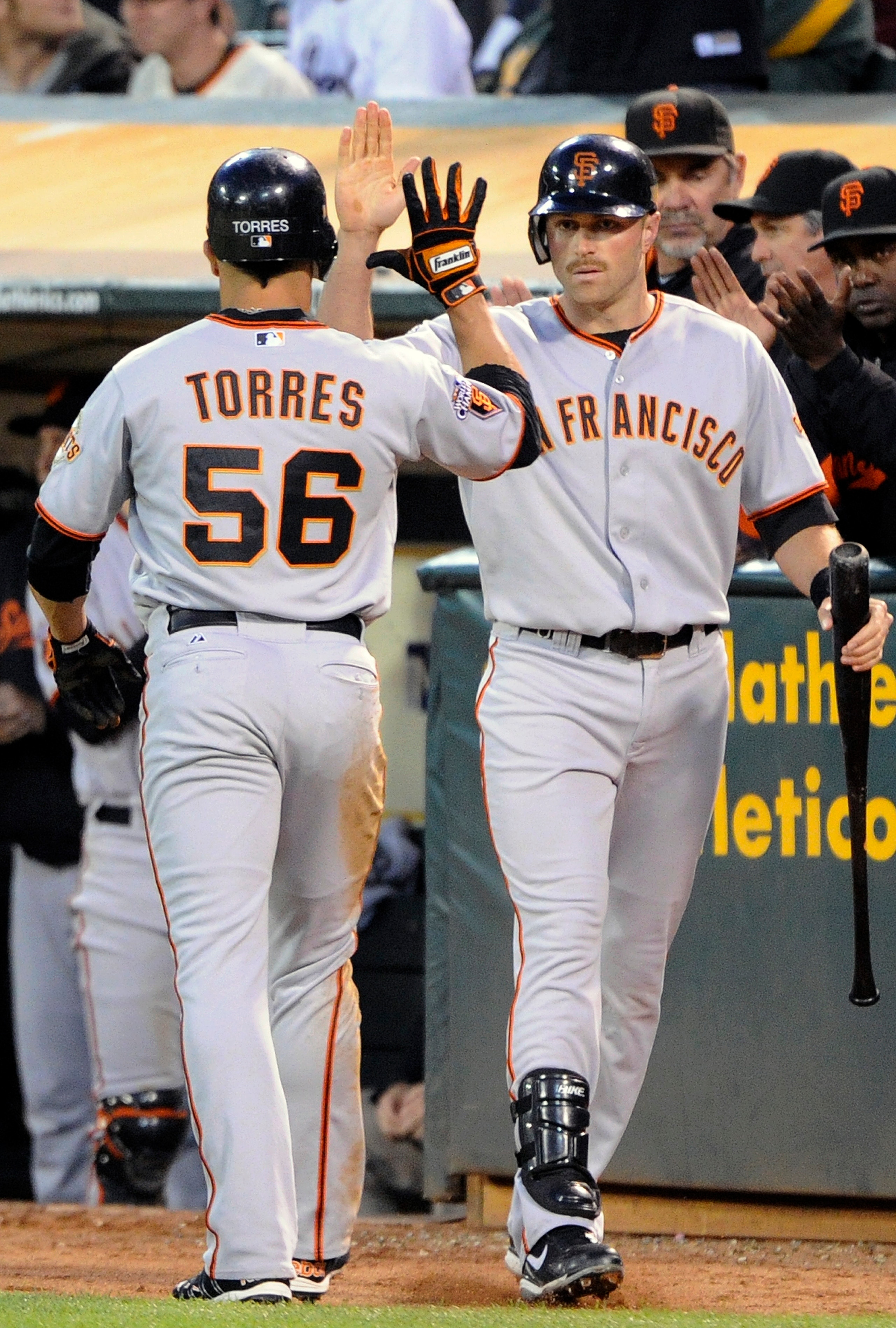 OAKLAND, CA -  JUNE 18: Andres Torres #56 of the San Francisco Giants after scoring on a sacrifice fly, high-fives Nate Schierholtz #12 against the Oakland Athletics during a MLB baseball game June 18, 2011 at the Oakland-Alameda County Coliseum in Oaklan