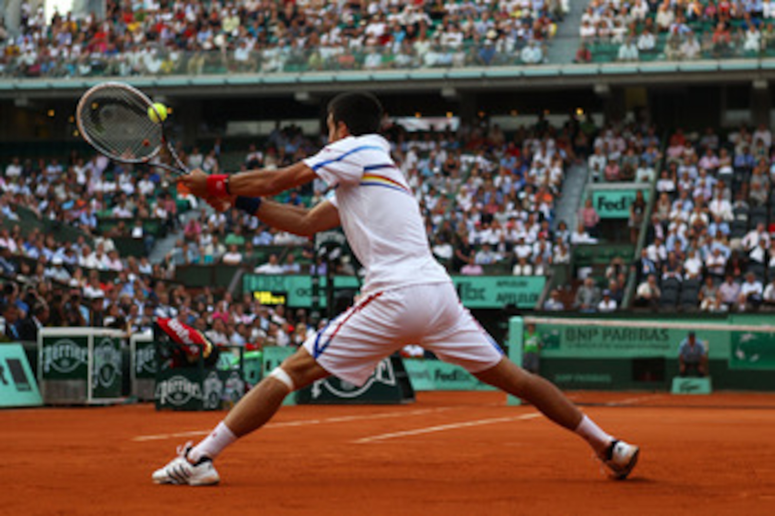 PARIS, FRANCE - JUNE 03:  Novak Djokovic of Serbia hits a backhand during the men's singles semi final match between Roger Federer of Switzerland and Novak Djokovic of Serbia on day thirteen of the French Open at Roland Garros on June 3, 2011 in Paris, Fr