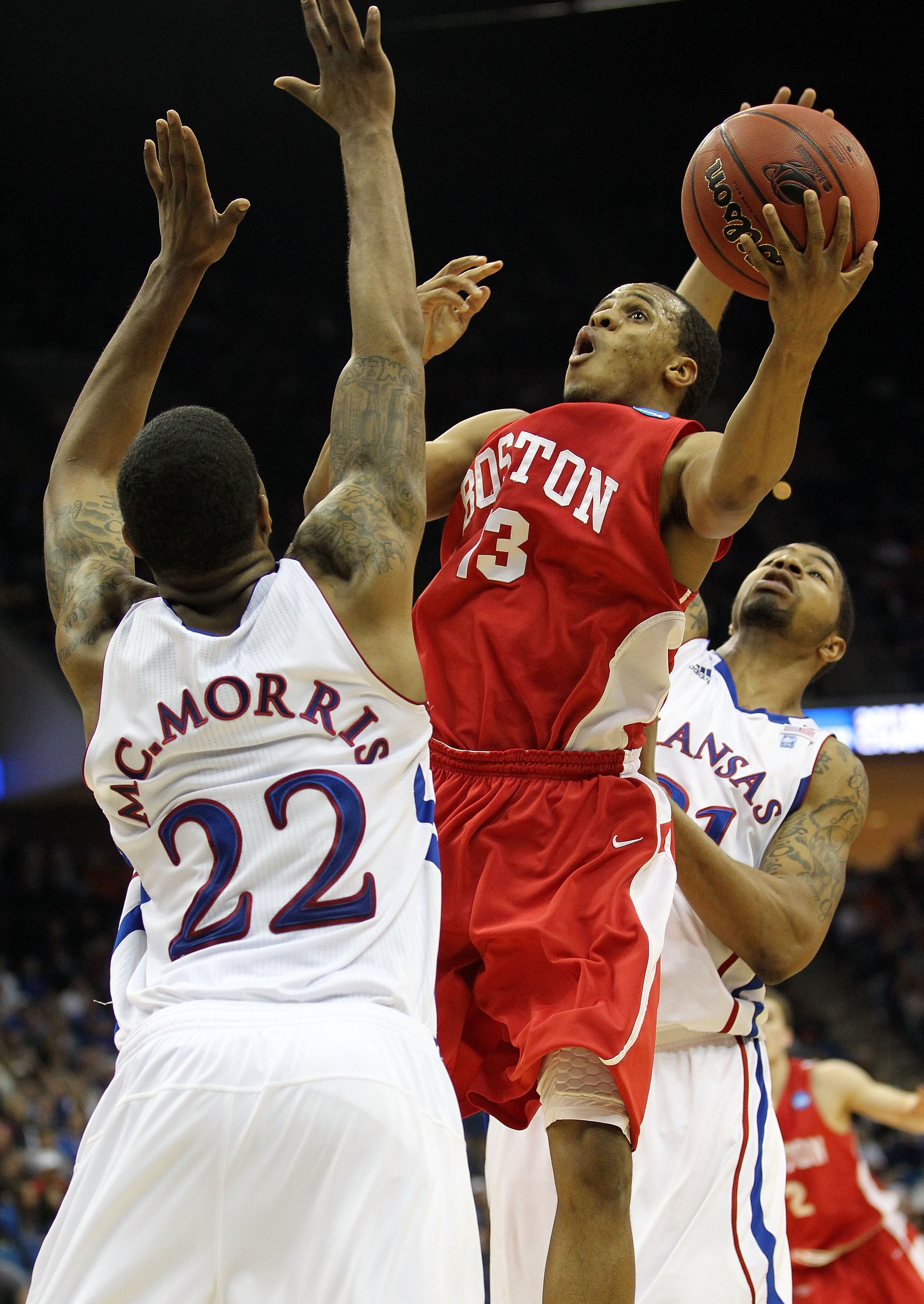 TULSA, OK - MARCH 18:  D.J. Irving #13 of the Boston University Terriers goes up for a shot against Marcus Morris #22 and Markieff Morris #21 of the Kansas Jayhawks during the second round of the 2011 NCAA men's basketball tournament at BOK Center on Marc